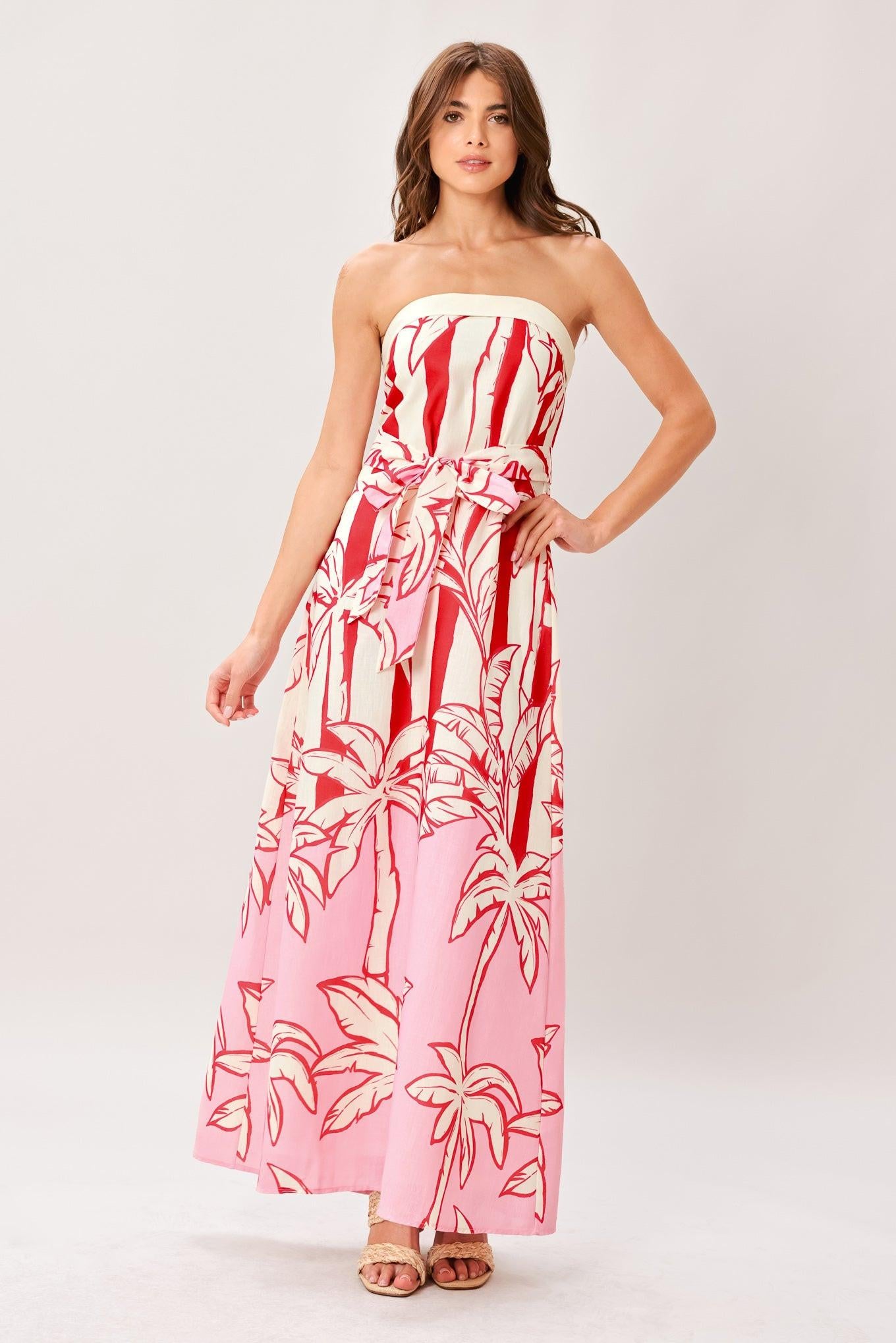 Woman wearing a red and white palm tree pattern printed woven ankle dress featuring strapless, front fold, self sash and back zipper closure