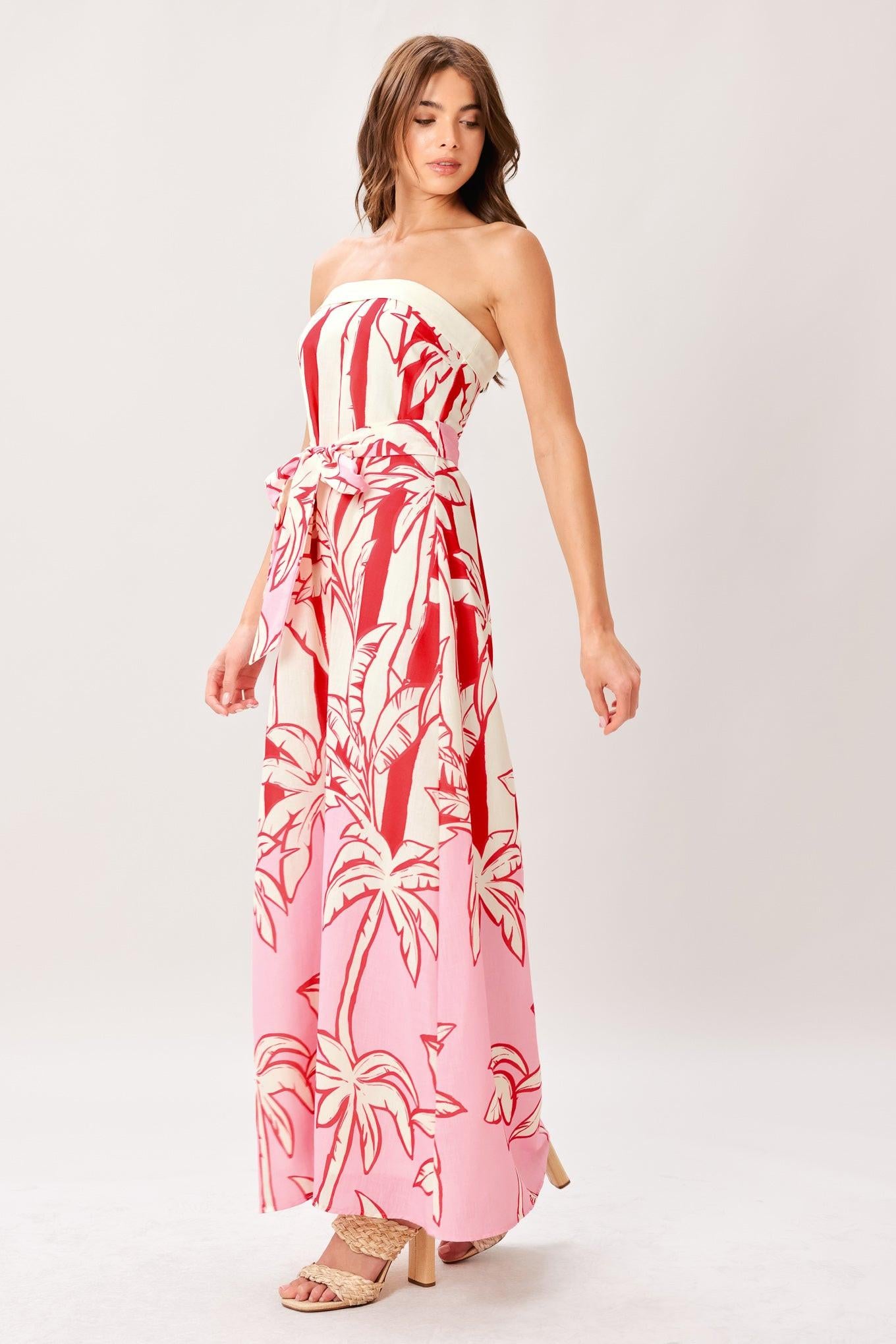 Woman wearing a red and white palm tree pattern printed woven ankle dress featuring strapless, front fold, self sash and back zipper closure