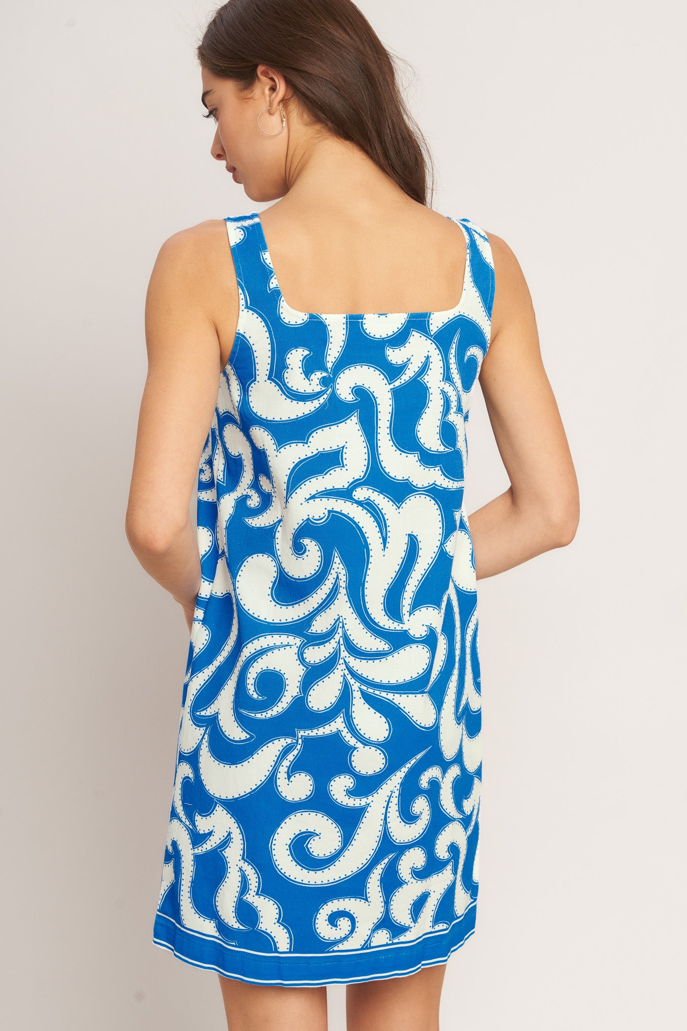 Woman wearing a blue and white patterned dress against a plain background