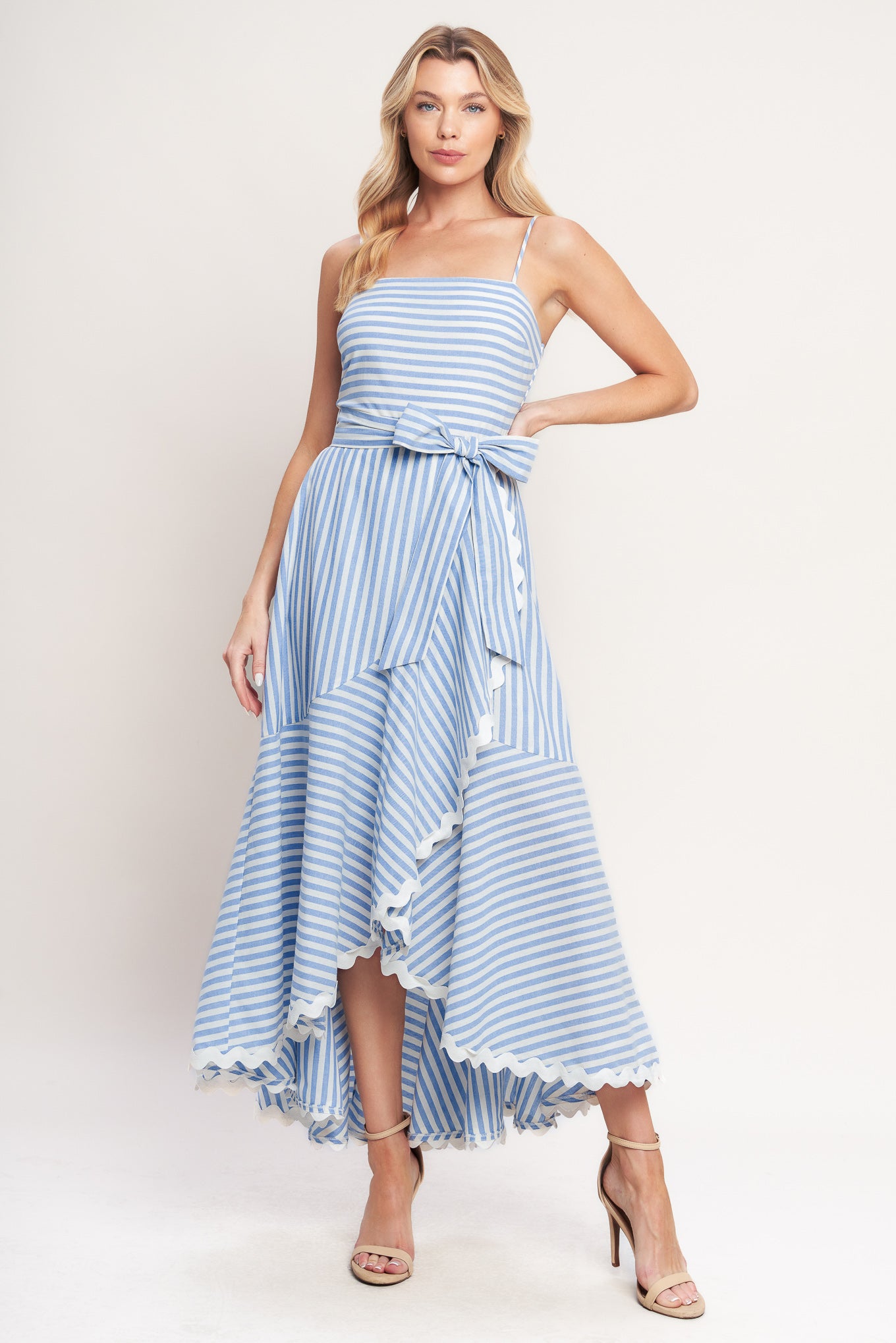 Blue-and-white striped midi dress with delicate straps, a waist bow tie, and a ruffled high-low hem

Details:

Self: 100% Cotton
Lining: 100% Polyester Exclusive of Decoration

Size & Fit

- Model is 5`8" And Wearing Size Small
- Measurements Taken From Size Small
- Approx. Length: 53"
