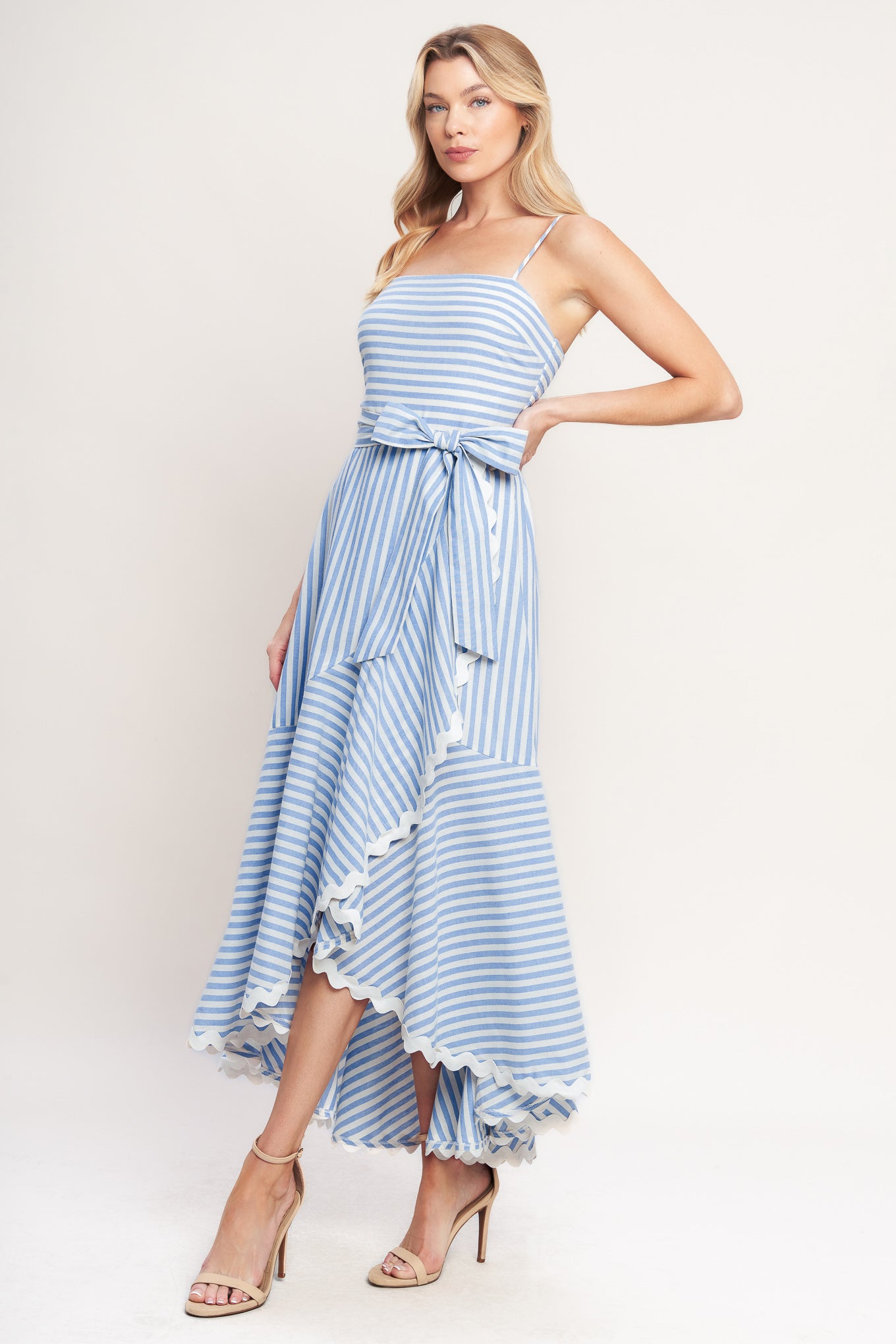 Blue-and-white striped midi dress with delicate straps, a waist bow tie, and a ruffled high-low hem

Details:

Self: 100% Cotton
Lining: 100% Polyester Exclusive of Decoration

Size & Fit

- Model is 5`8" And Wearing Size Small
- Measurements Taken From Size Small
- Approx. Length: 53"
