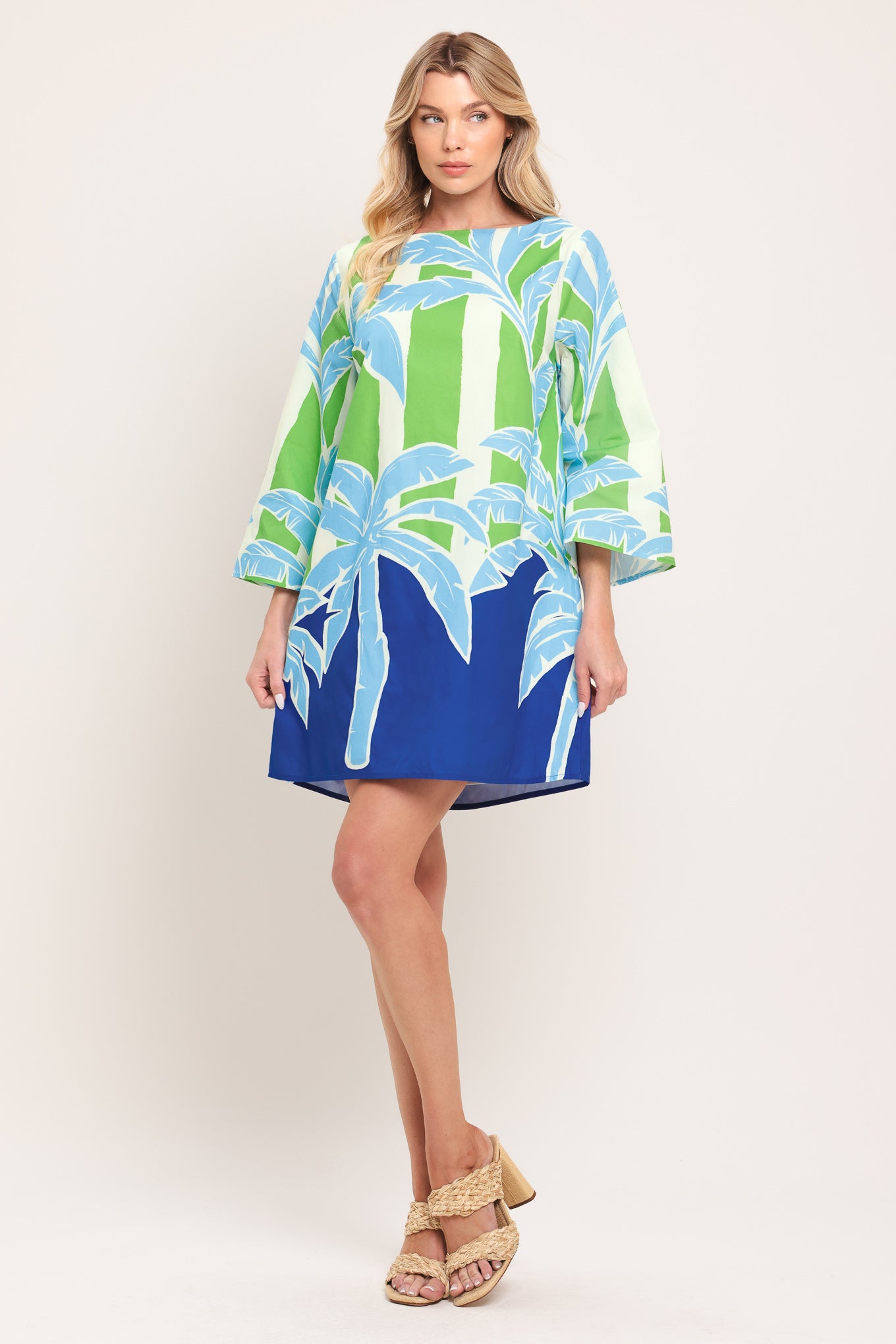Woman wearing a colorful green and blue mini dress with palm tree design | Flying Tomato