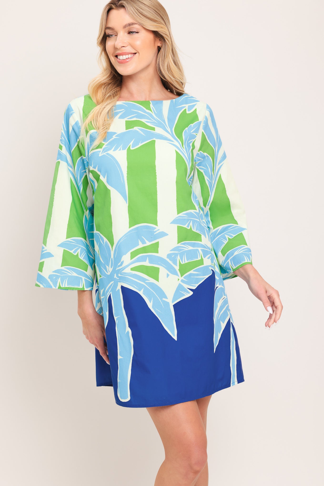Woman wearing a colorful green and blue mini dress with palm tree design | Flying Tomato