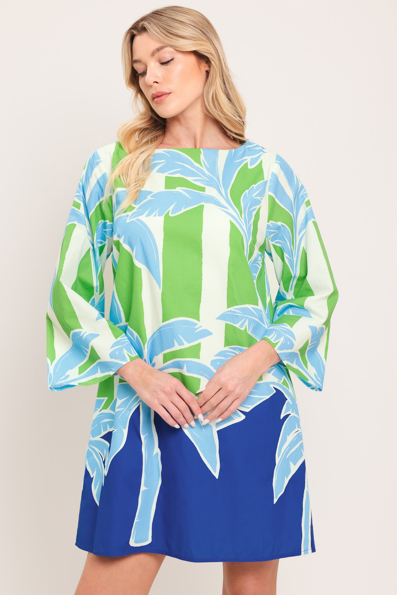 Woman wearing a colorful green and blue mini dress with palm tree design | Flying Tomato
