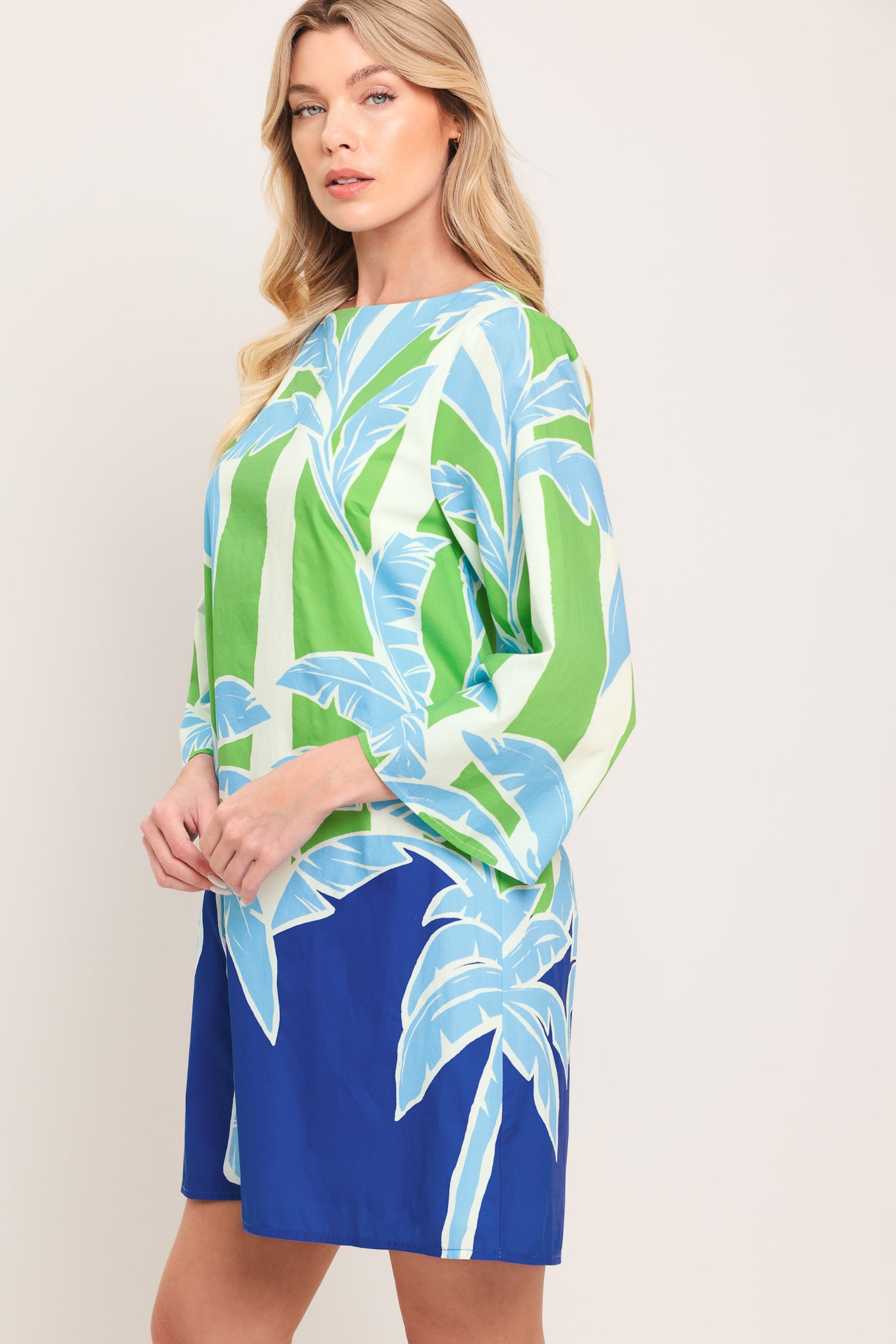 Woman wearing a colorful green and blue mini dress with palm tree design | Flying Tomato