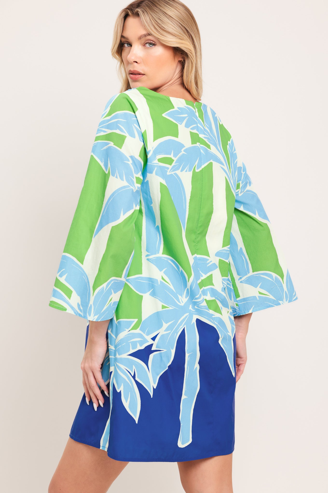 Woman wearing a colorful green and blue mini dress with palm tree design | Flying Tomato