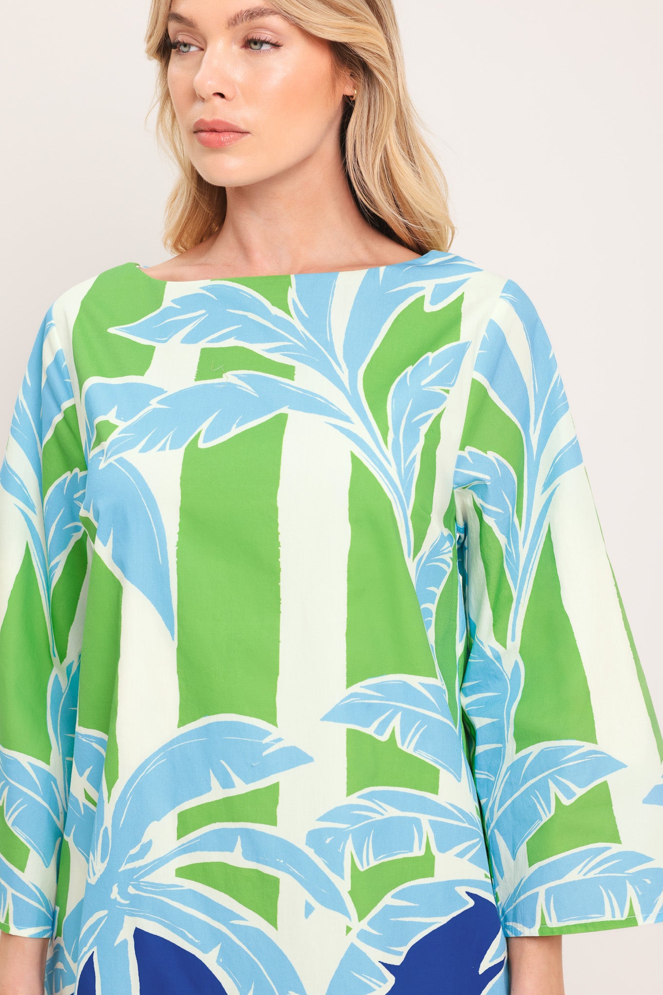 Woman wearing a colorful green and blue mini dress with palm tree design | Flying Tomato