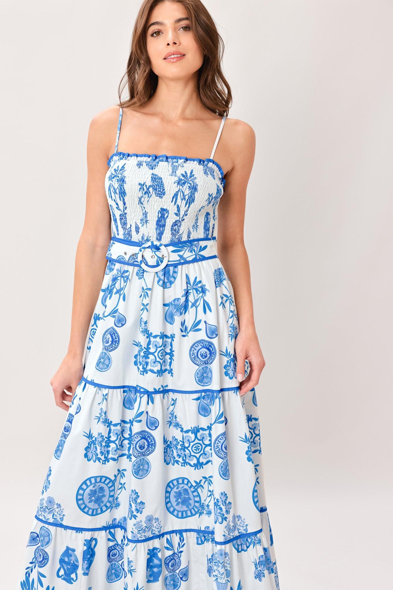 Woman wearing a blue and white patterned printed woven maxi dress featuring smocked bodice, straps, self belt and tier skirt