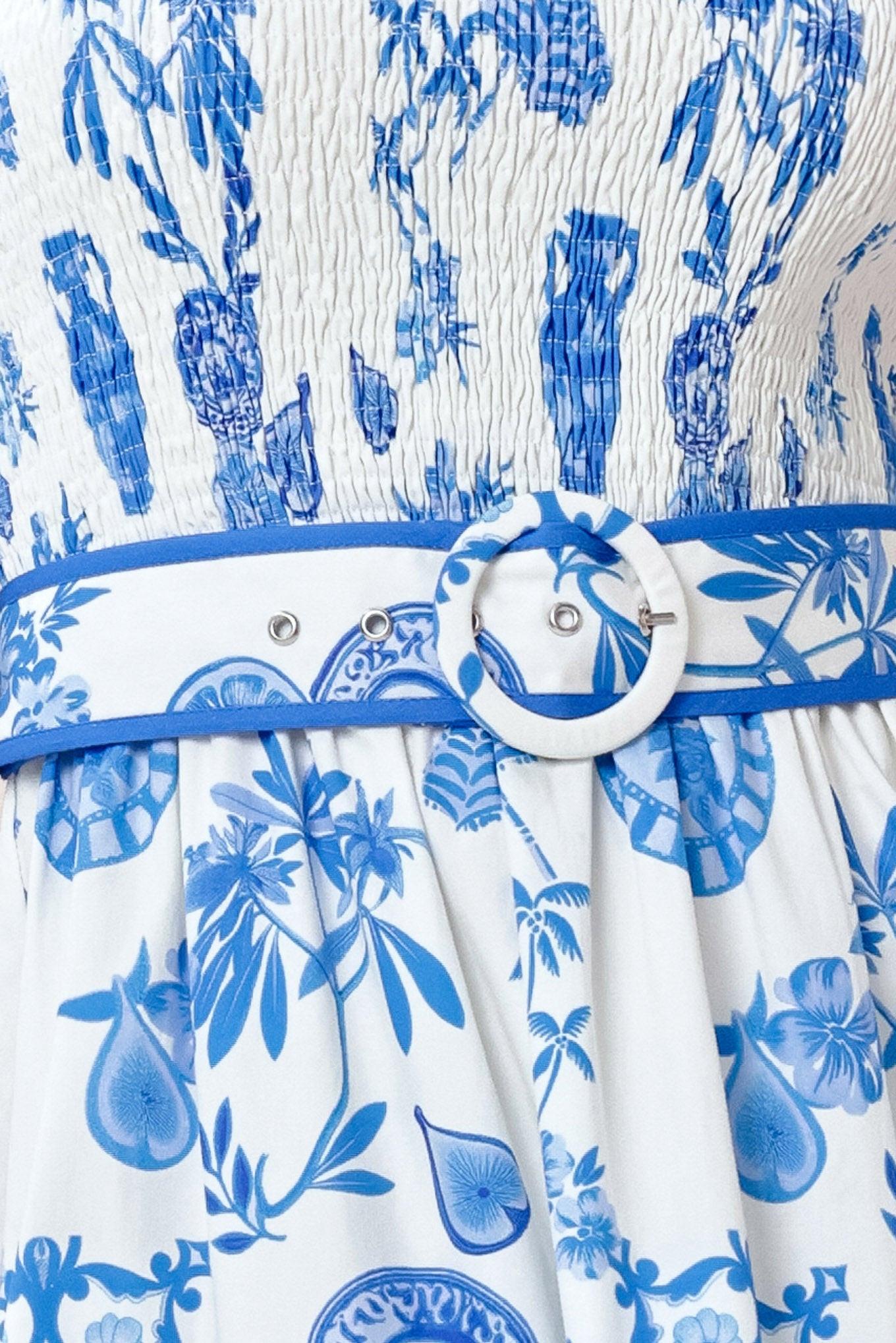 White dress with blue floral pattern and a belt with a circular buckle.