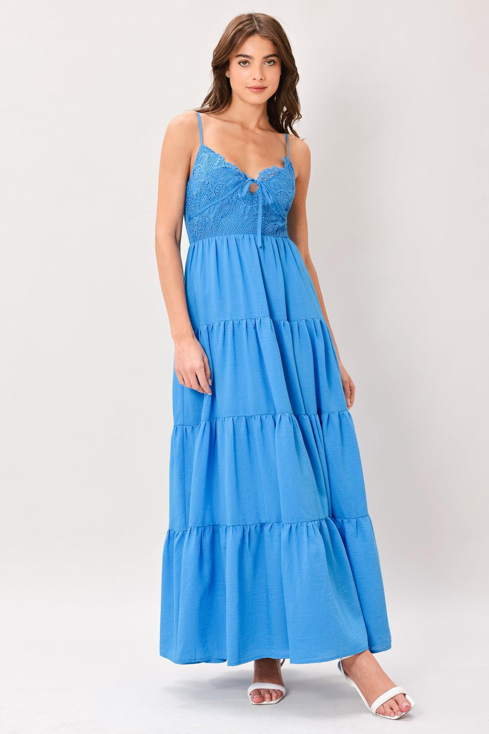 Woman wearing a blue tiered solid woven maxi dress featuring lace bodice with front tie, straps, tier skirt and smocked back bodice