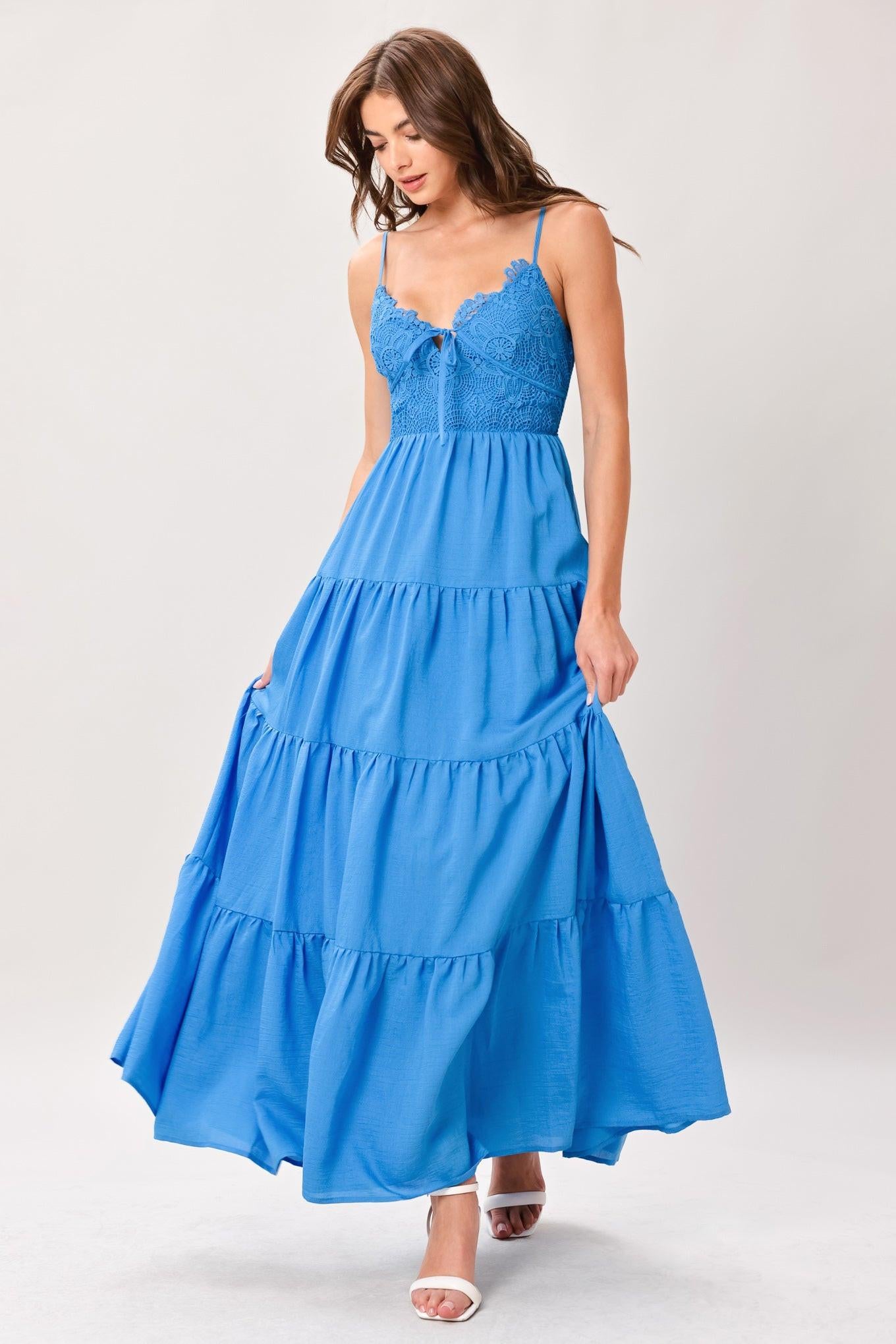 Woman wearing a blue tiered solid woven maxi dress featuring lace bodice with front tie, straps, tier skirt and smocked back bodice