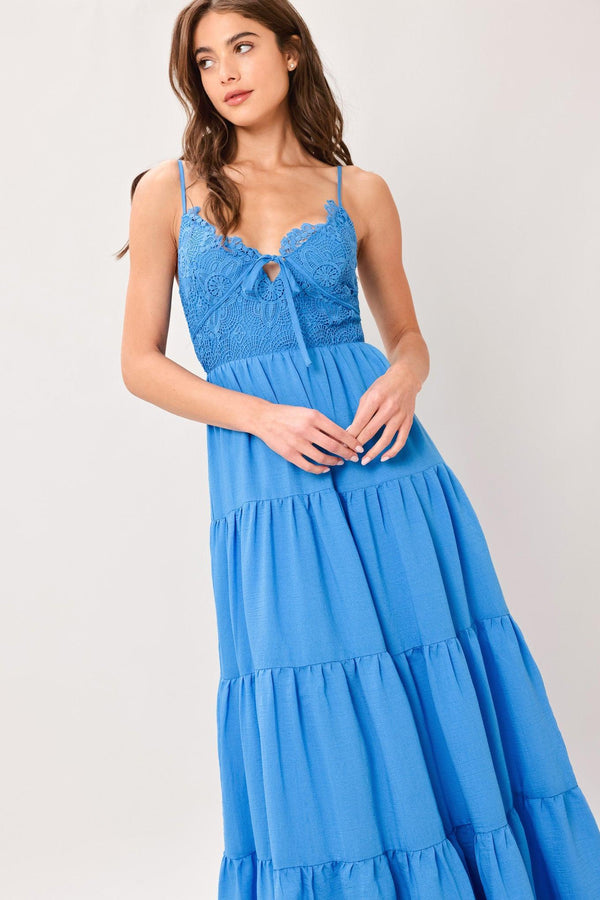 Woman wearing a blue tiered solid woven maxi dress featuring lace bodice with front tie, straps, tier skirt and smocked back bodice