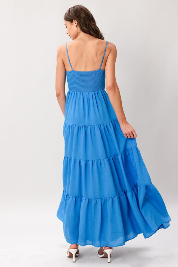 Woman wearing a blue tiered solid woven maxi dress featuring lace bodice with front tie, straps, tier skirt and smocked back bodice