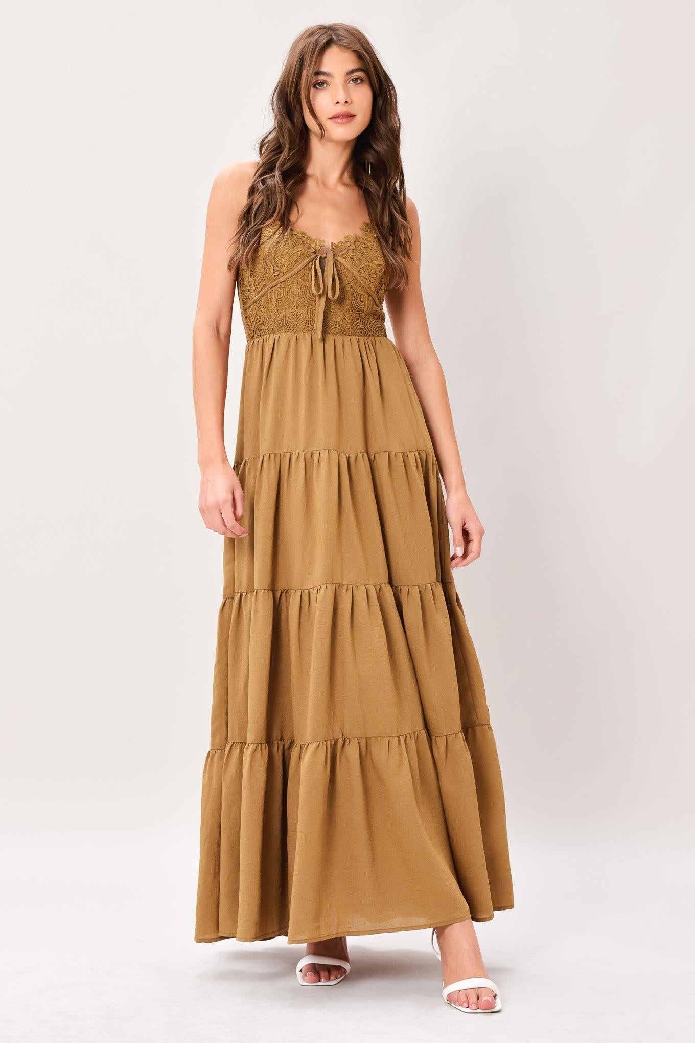 Woman wearing a brown tiered solid woven maxi dress featuring lace bodice with front tie, straps, tier skirt and smocked back bodice