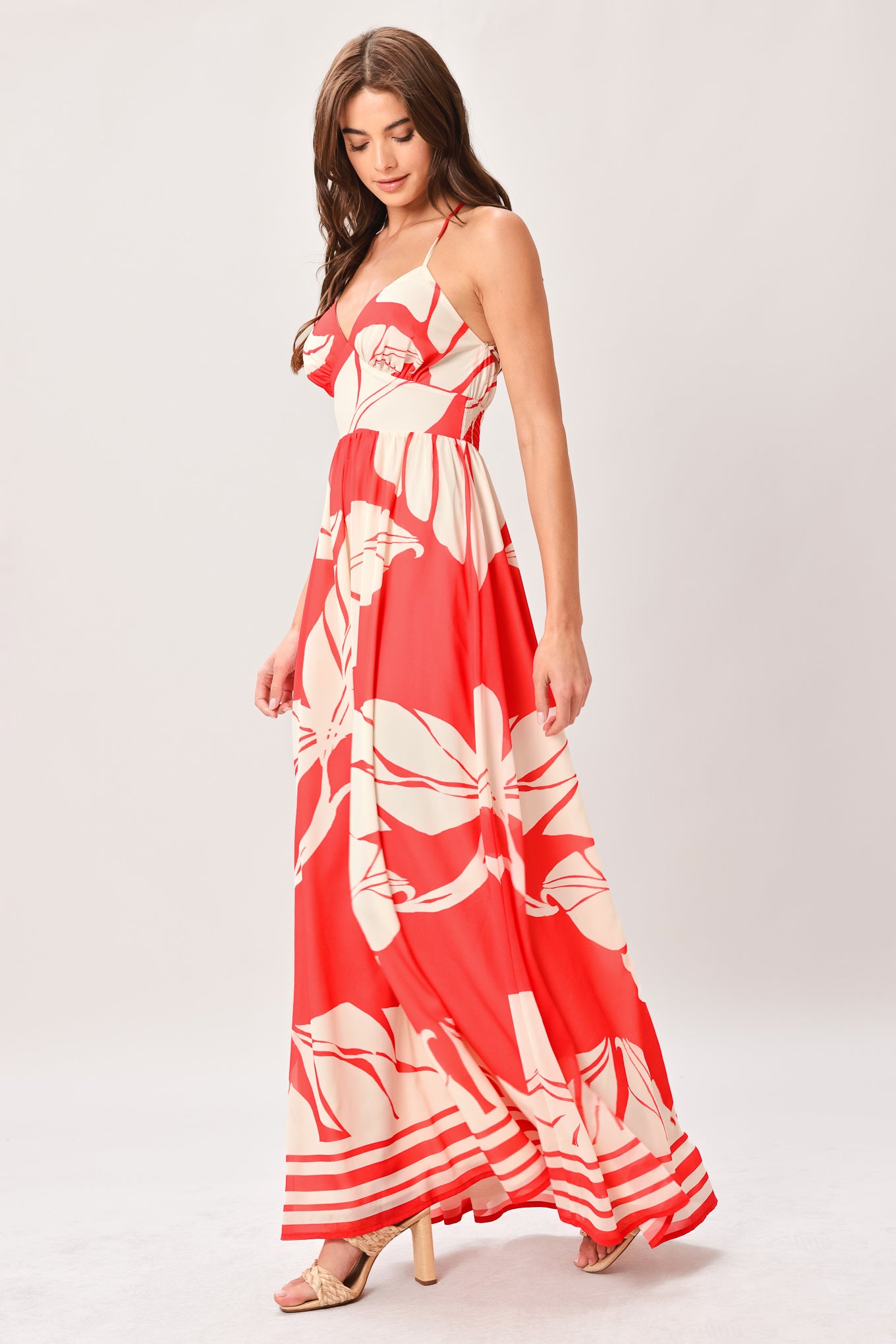 Woman wearing a red floral maxi dress featuring cami top, waist yoke, full skirt, bare back with tie and smocked waistband | Flying Tomato