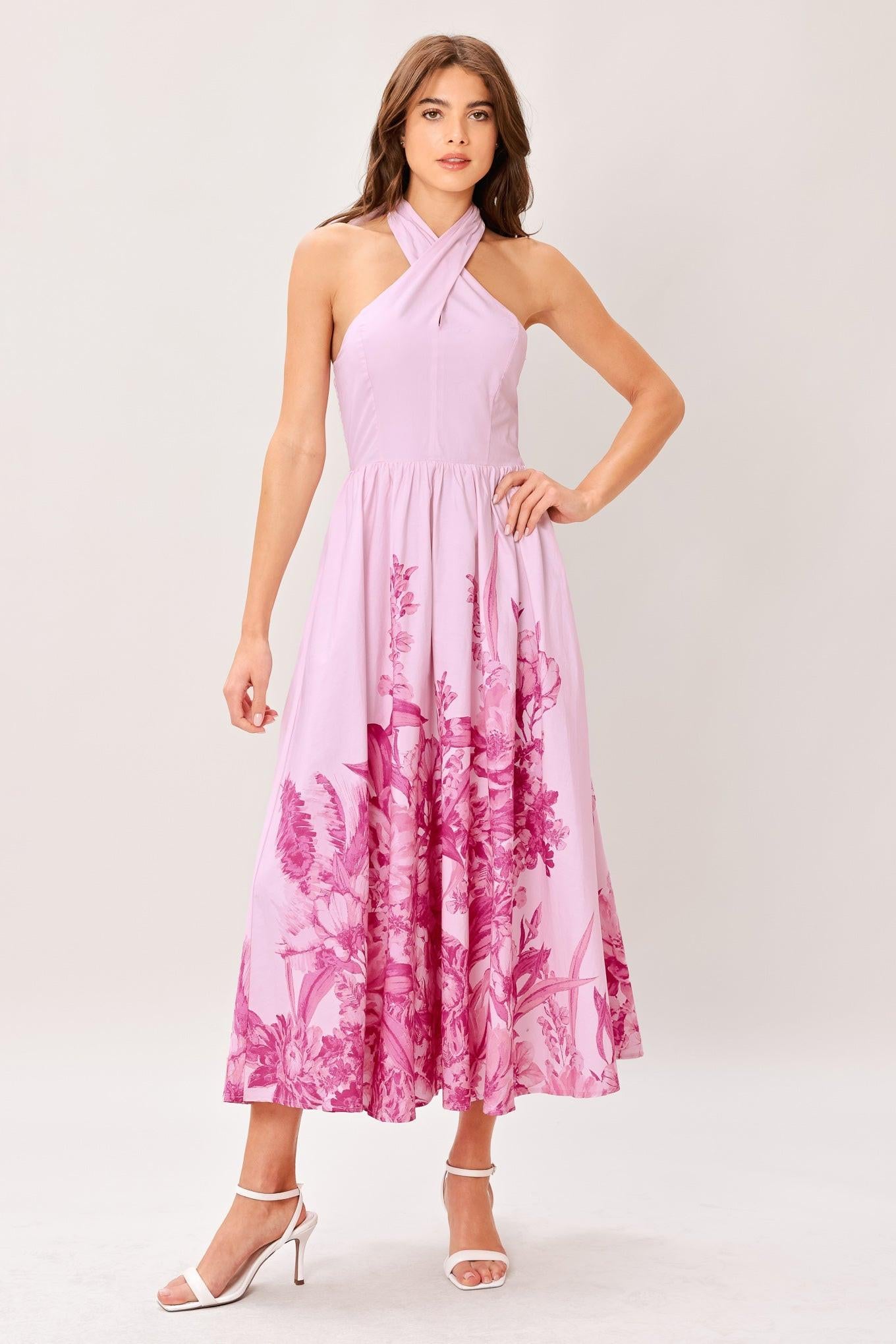 Woman wearing a pink floral printed woven midi dress featuring twist front with back neck tie, full skirt and smocked back bodice