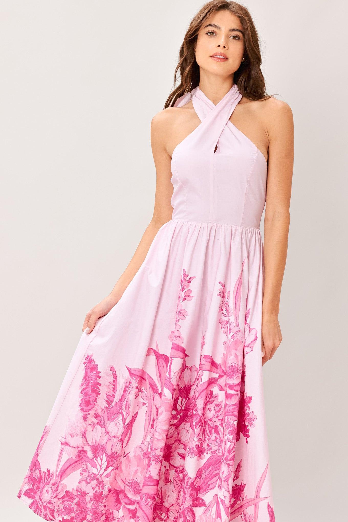 Woman wearing a pink floral printed woven midi dress featuring twist front with back neck tie, full skirt and smocked back bodice