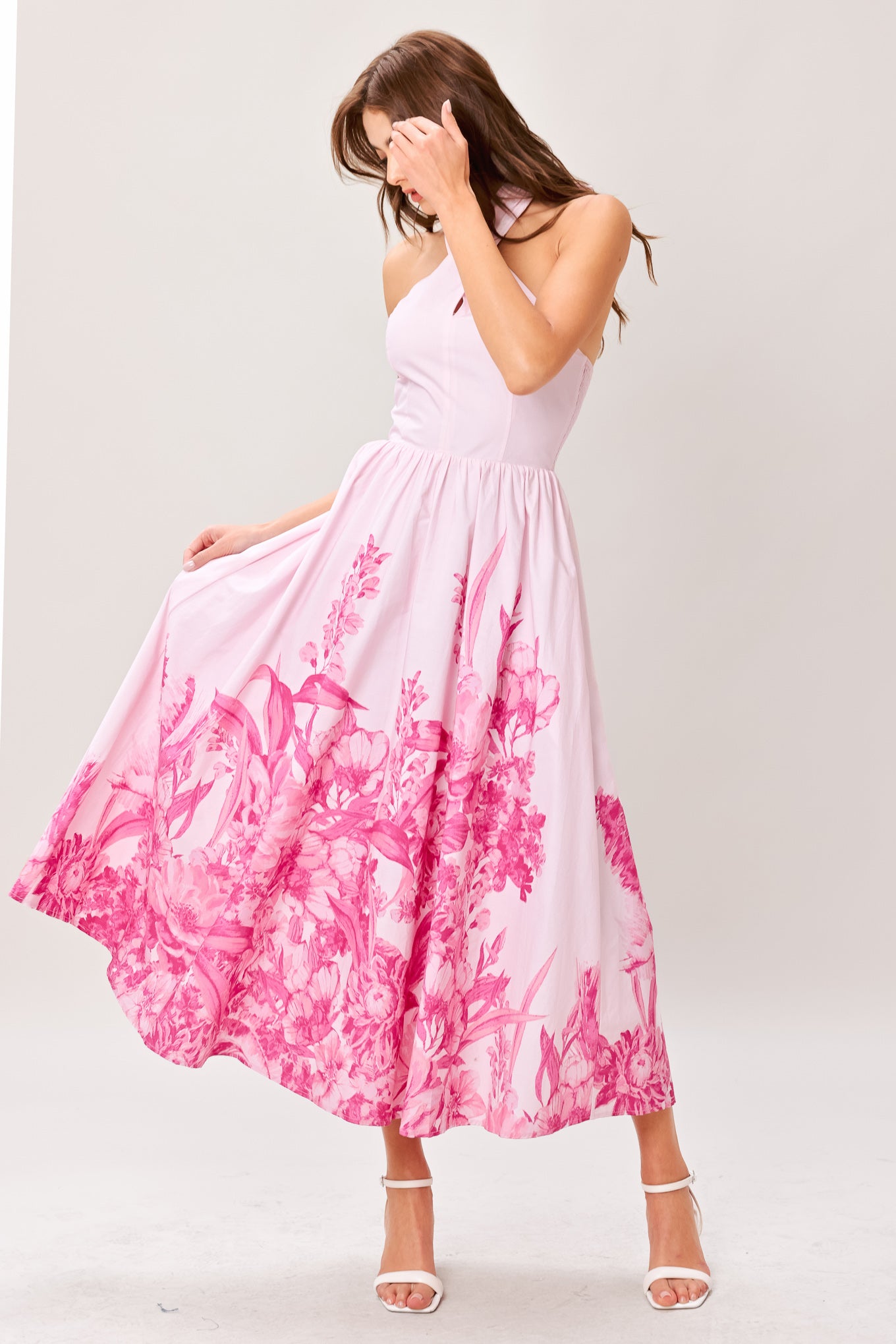 Woman wearing a pink floral printed woven midi dress featuring twist front with back neck tie, full skirt and smocked back bodice