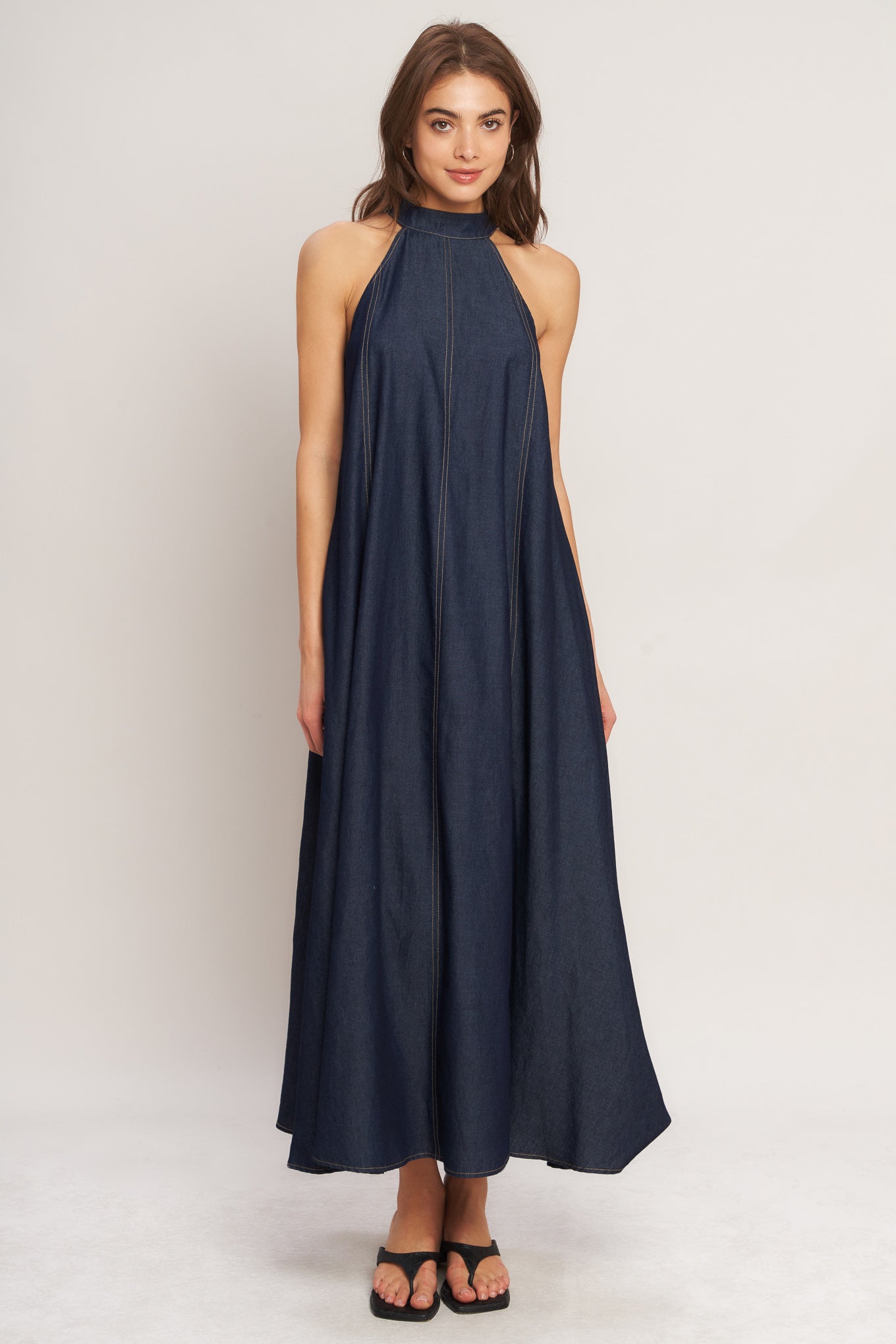 A solid woven midi halter dress with back neck button closure and side pockets