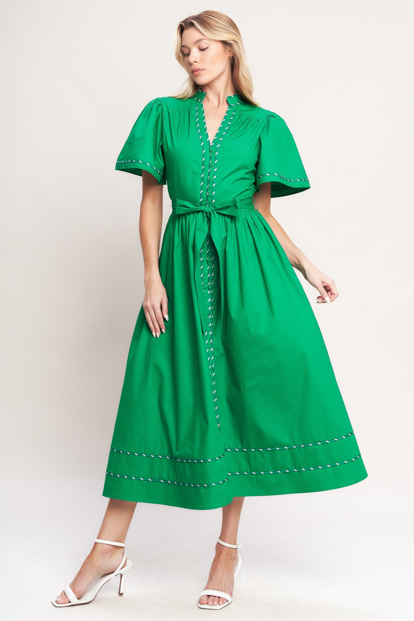 Woman wearing a green midi dress featuring V neckline, short flutter sleeve, button down, self sash tie, contrasting binding and full skirt | Flying Tomato