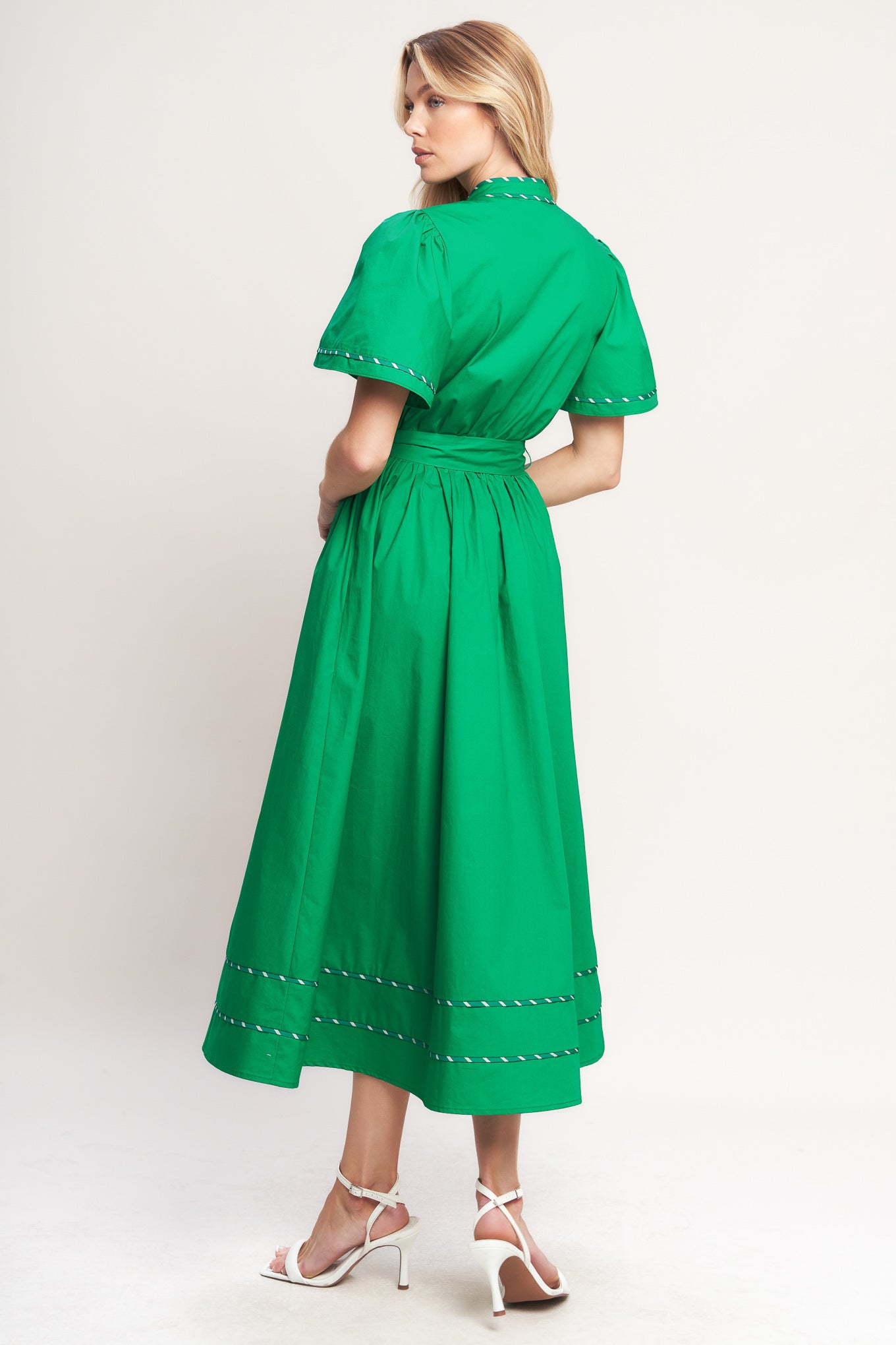 Woman wearing a green midi dress featuring V neckline, short flutter sleeve, button down, self sash tie, contrasting binding and full skirt | Flying Tomato