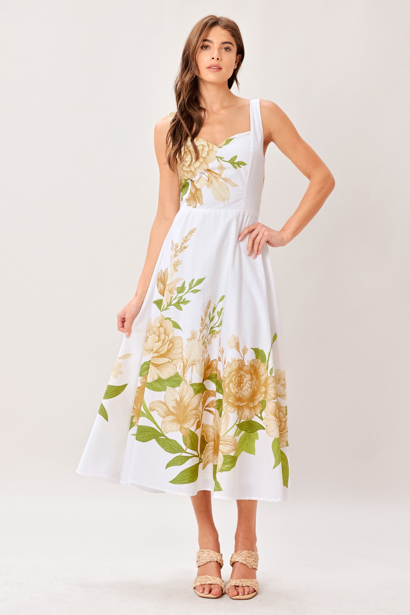 Woman wearing a white dress with yellow floral patterns on a white background