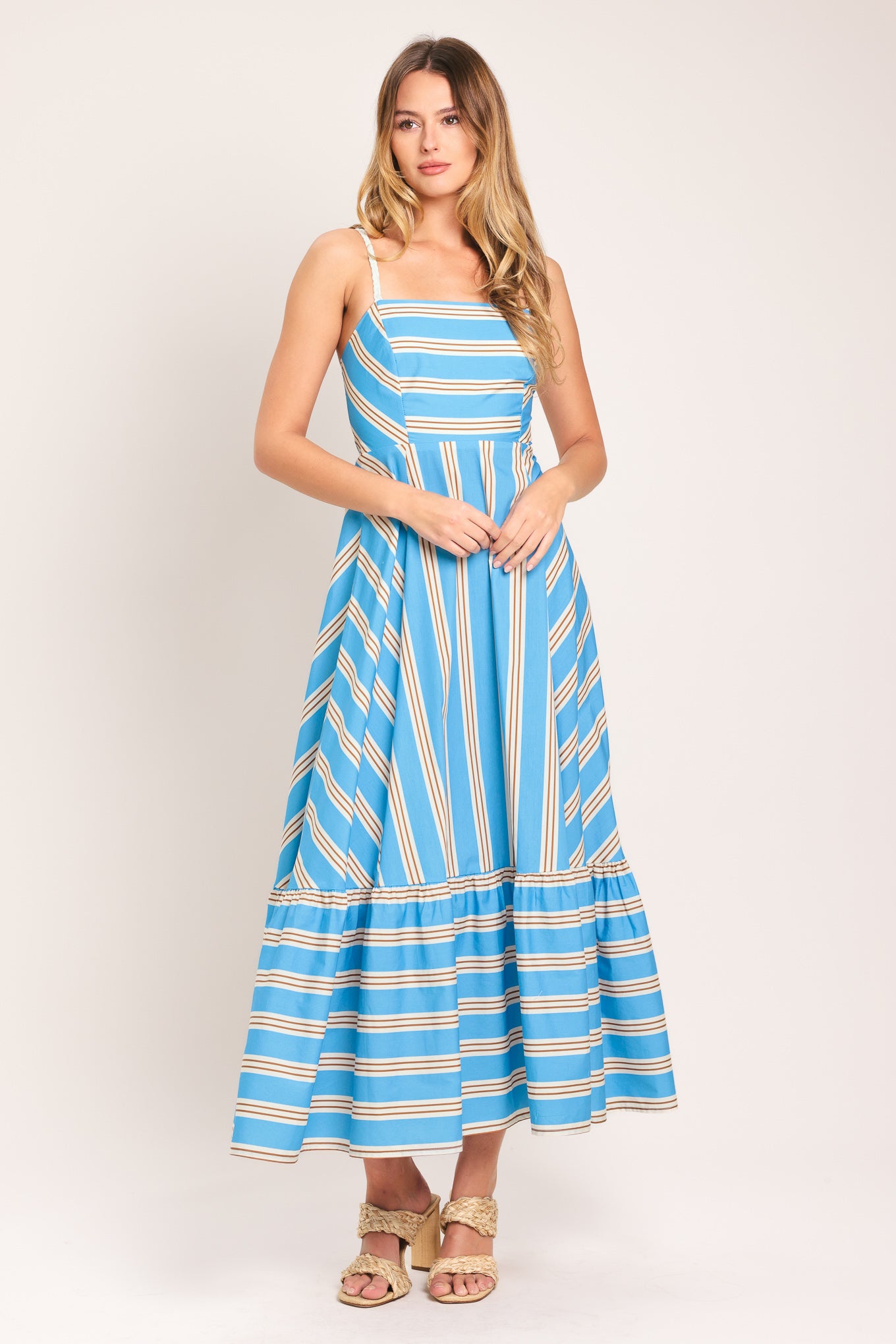 Woman wearing a blue and white striped midi dress featuring straight neckline, braided strap, circle skirt, ruffle hem, bare back with tie closure | Flying Tomato