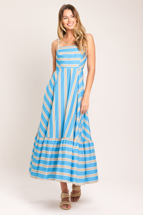 Woman wearing a blue and white striped midi dress featuring straight neckline, braided strap, circle skirt, ruffle hem, bare back with tie closure | Flying Tomato