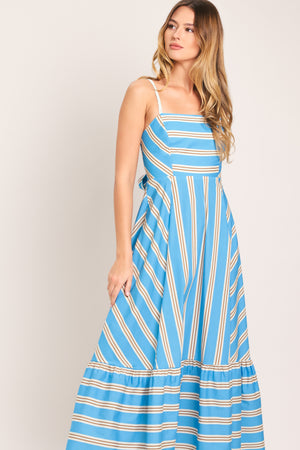 Woman wearing a blue and white striped midi dress featuring straight neckline, braided strap, circle skirt, ruffle hem, bare back with tie closure | Flying Tomato