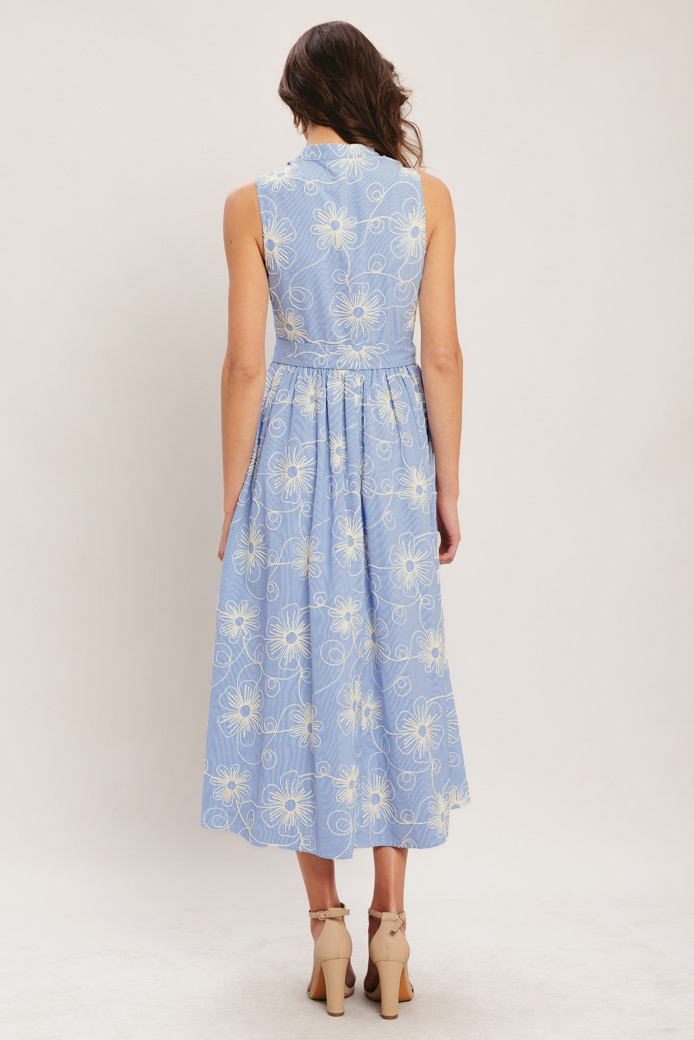 Woman wearing a light blue floral dress on a white background