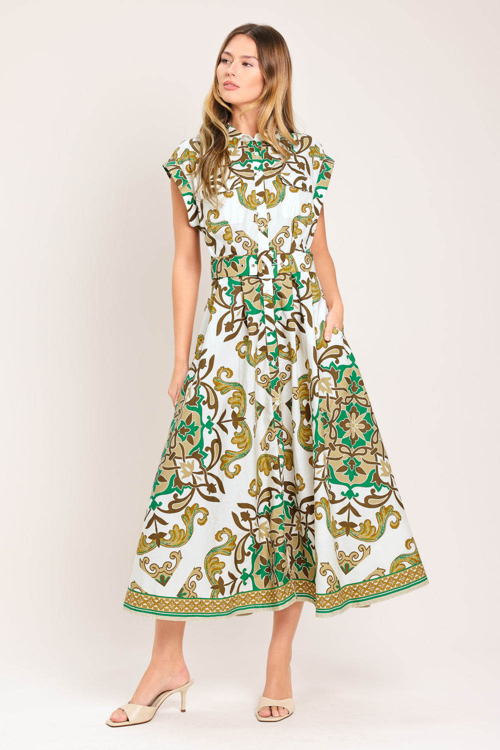 Woman wearing a green, brown, and white patterned midi shirt dress featuring cuffed short sleeve, front button down, self belt and side pockets | Flying Tomato