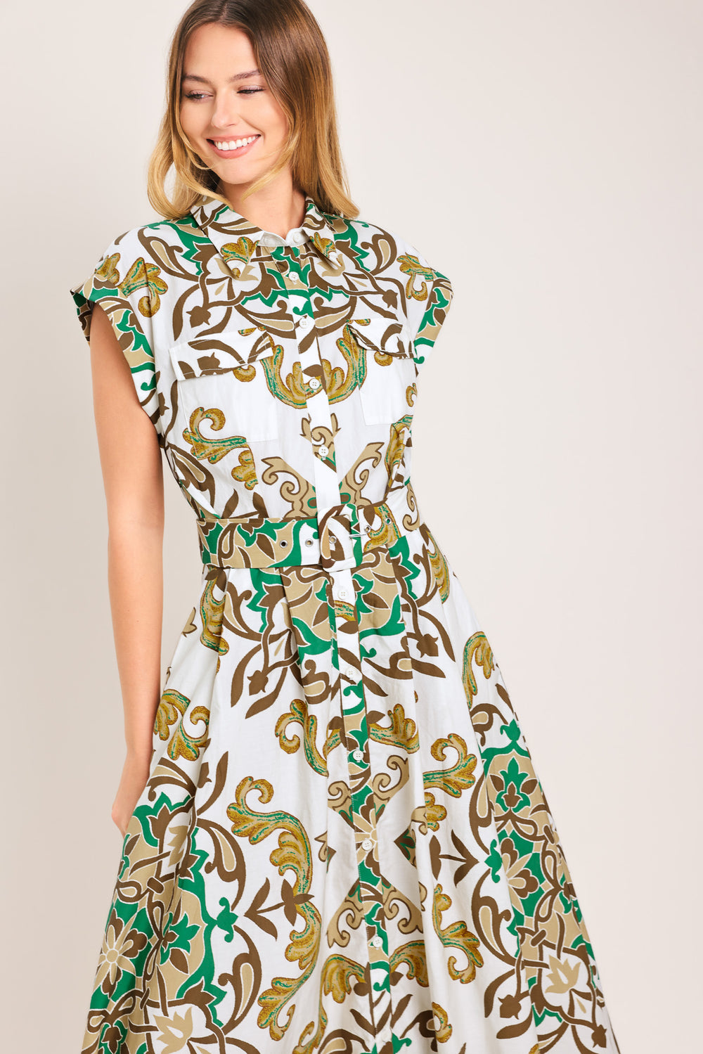Woman wearing a green, brown, and white patterned midi shirt dress featuring cuffed short sleeve, front button down, self belt and side pockets | Flying Tomato