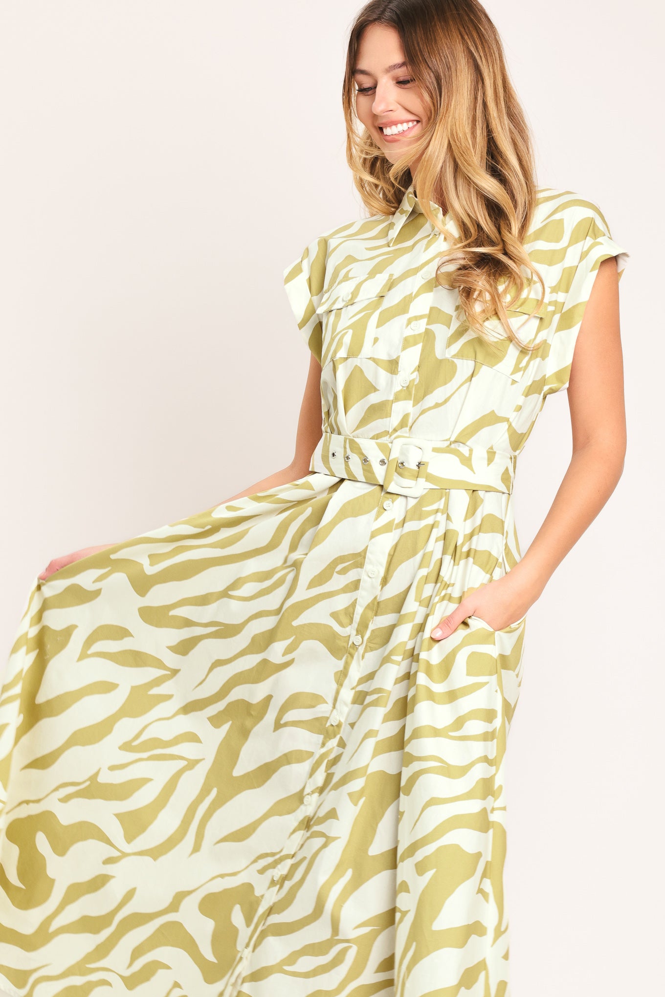 Woman wearing an ivory with taupe zebra printed midi shirt dress featuring cuffed short sleeve, front button down, self belt and side pockets | Flying Tomato