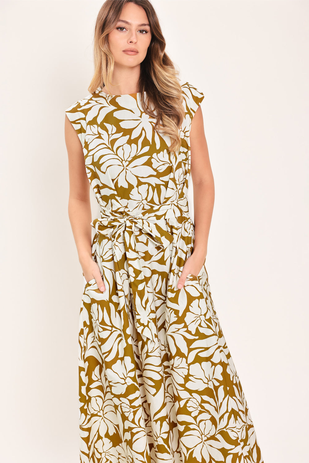 Woman wearing a camel and white short sleeve midi dress with round neckline, self sash and back neck button closure with a tropical floral pattern | Flying Tomato