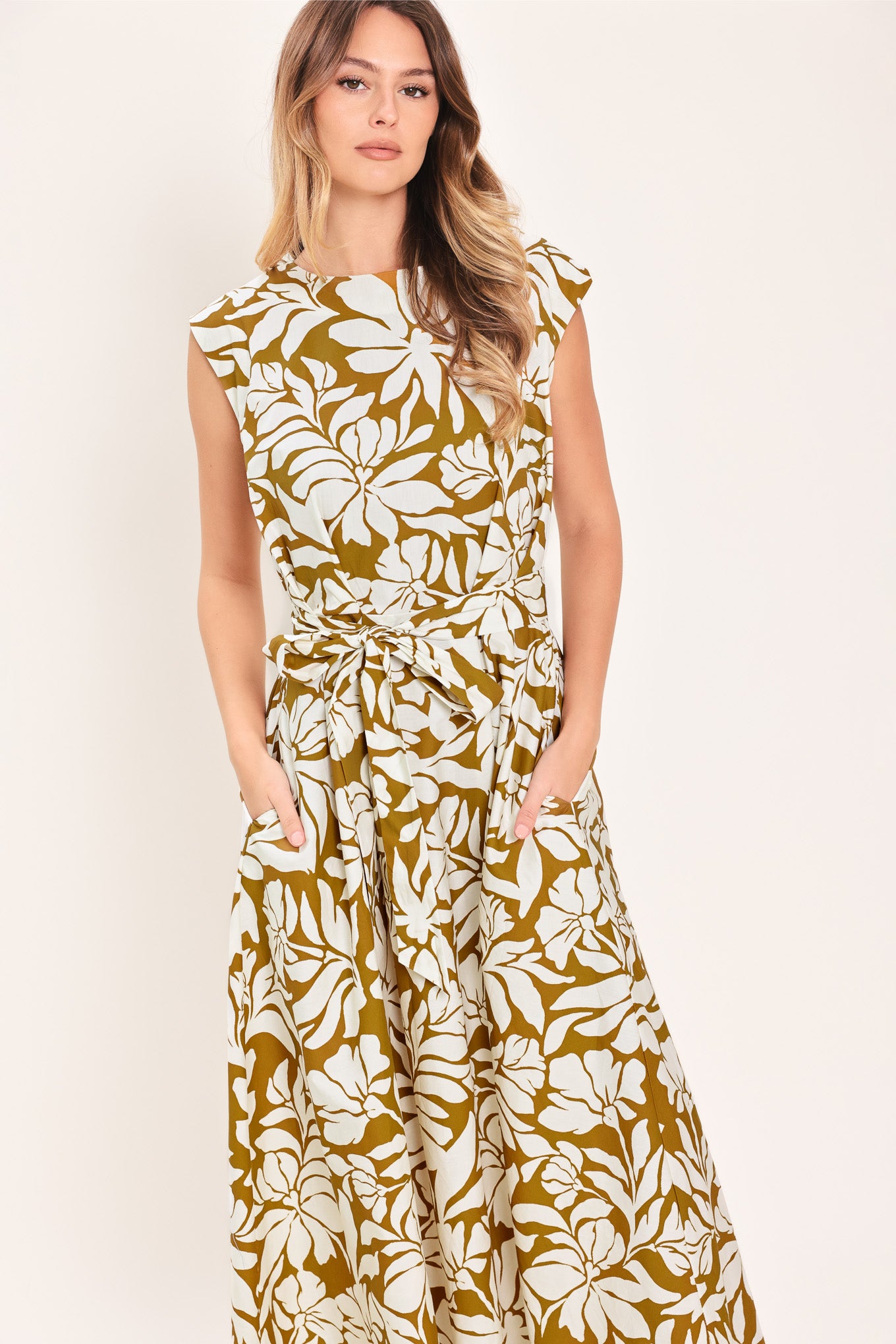 Woman wearing a camel and white short sleeve midi dress with round neckline, self sash and back neck button closure with a tropical floral pattern | Flying Tomato