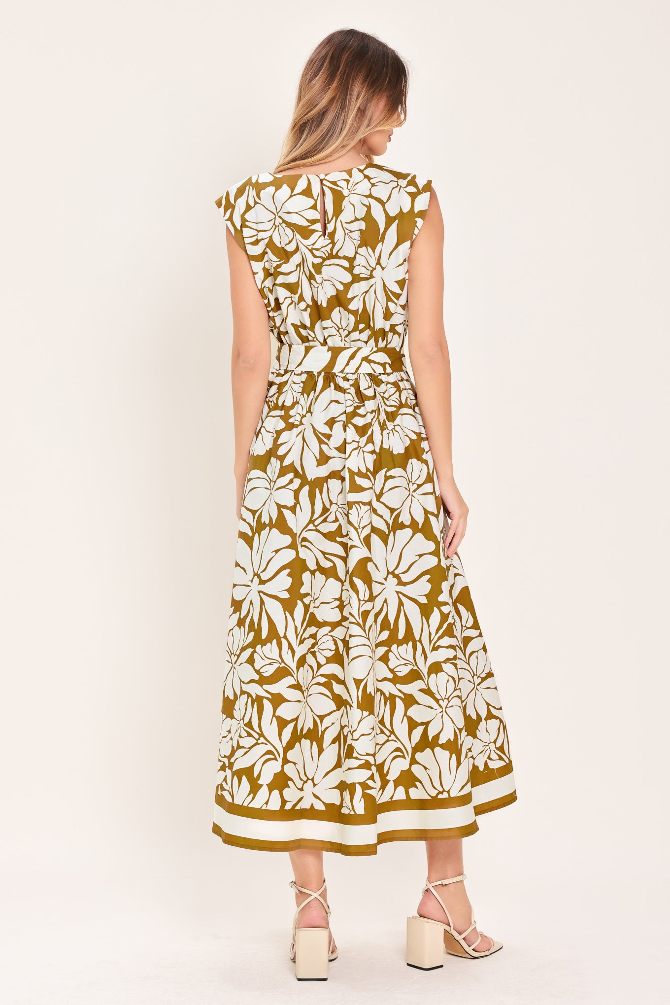 Woman wearing a camel and white short sleeve midi dress with round neckline, self sash and back neck button closure with a tropical floral pattern | Flying Tomato