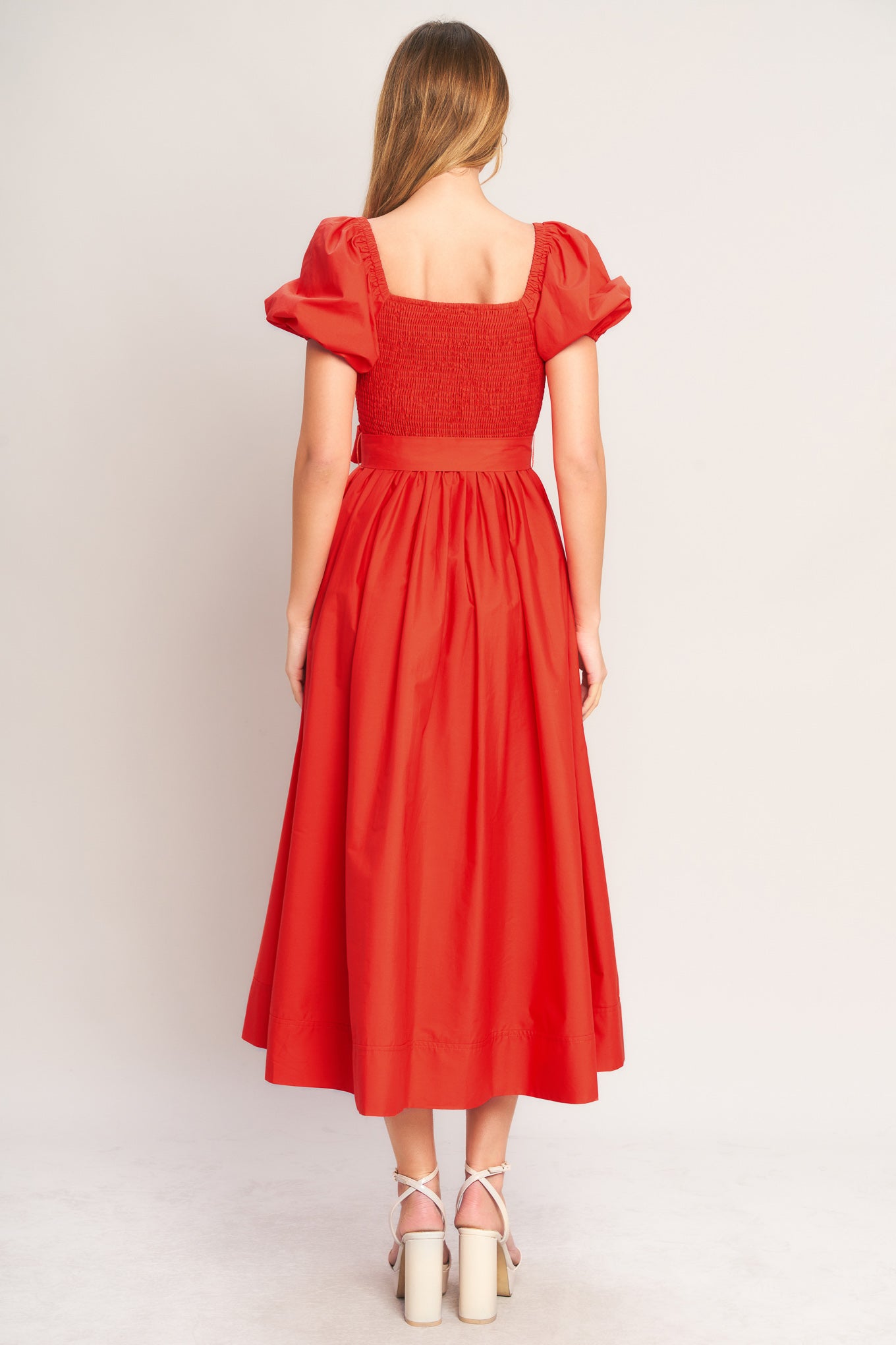 Red dress with puff sleeves worn by a person on a plain background
