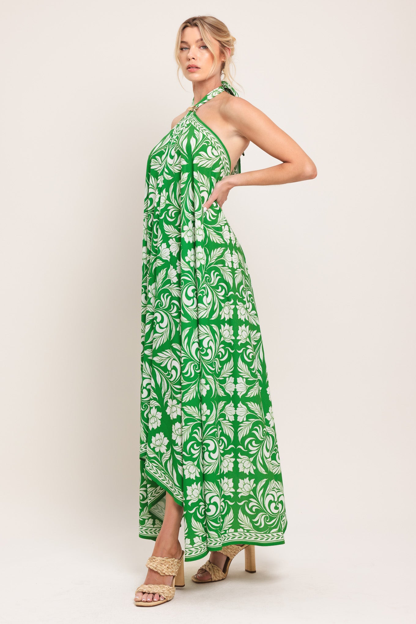 Woman wearing a green and white patterned halter neck midi dress with hardware detail, bare back, and tie closure | Flying Tomato