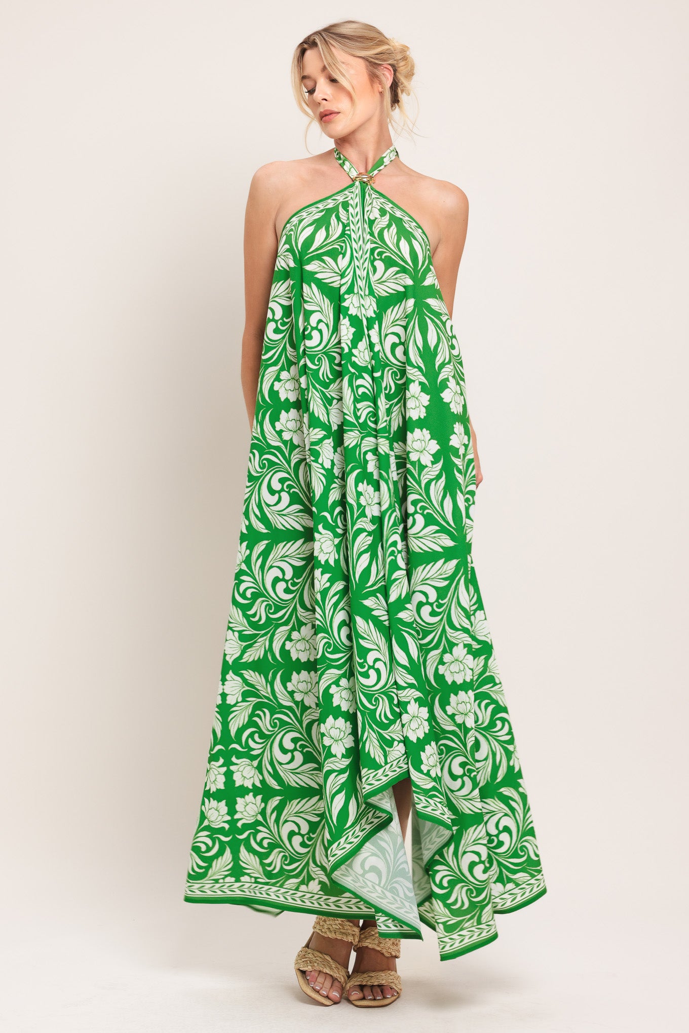 Woman wearing a green and white patterned halter neck midi dress with hardware detail, bare back, and tie closure | Flying Tomato