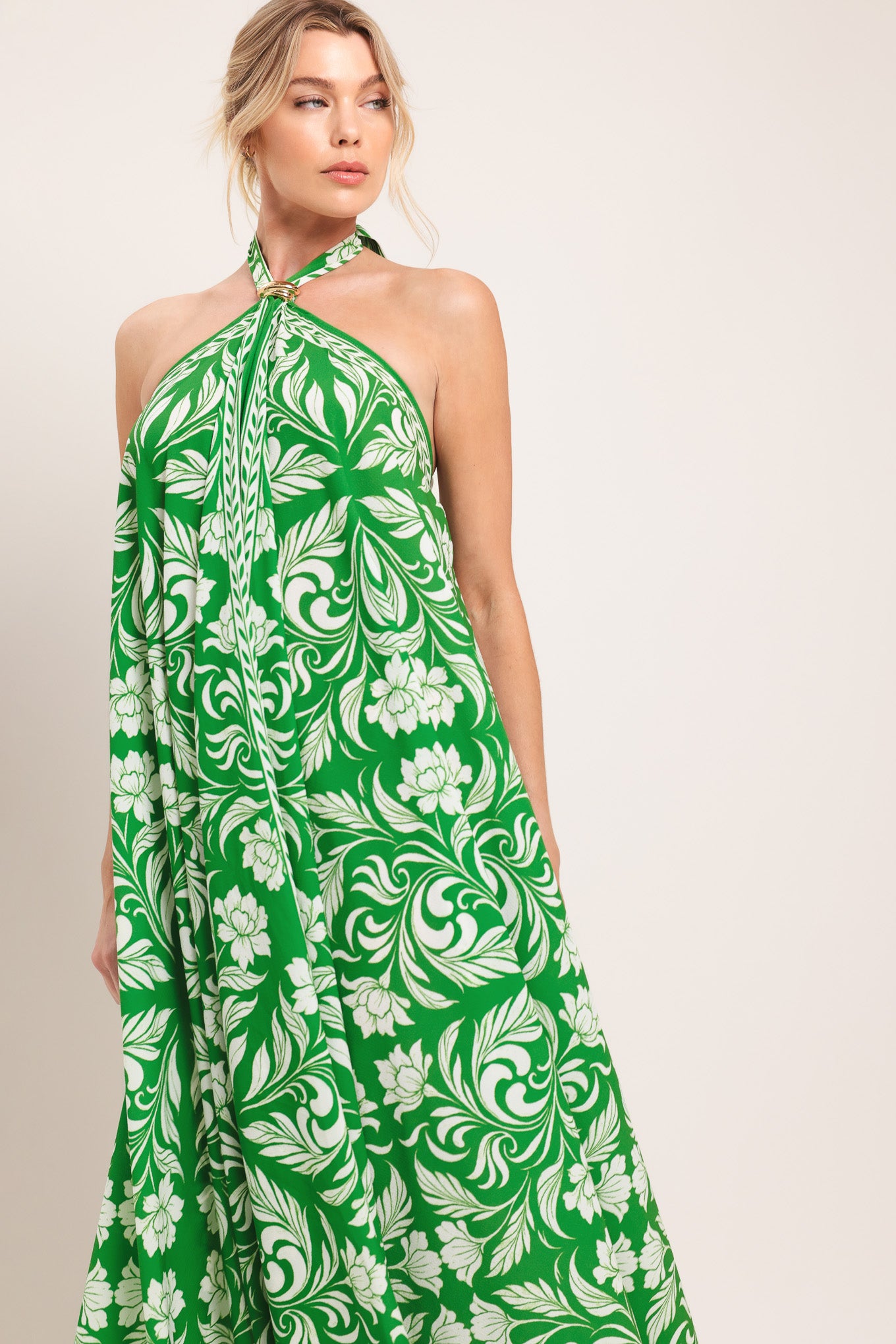 Woman wearing a green and white patterned halter neck midi dress with hardware detail, bare back, and tie closure | Flying Tomato