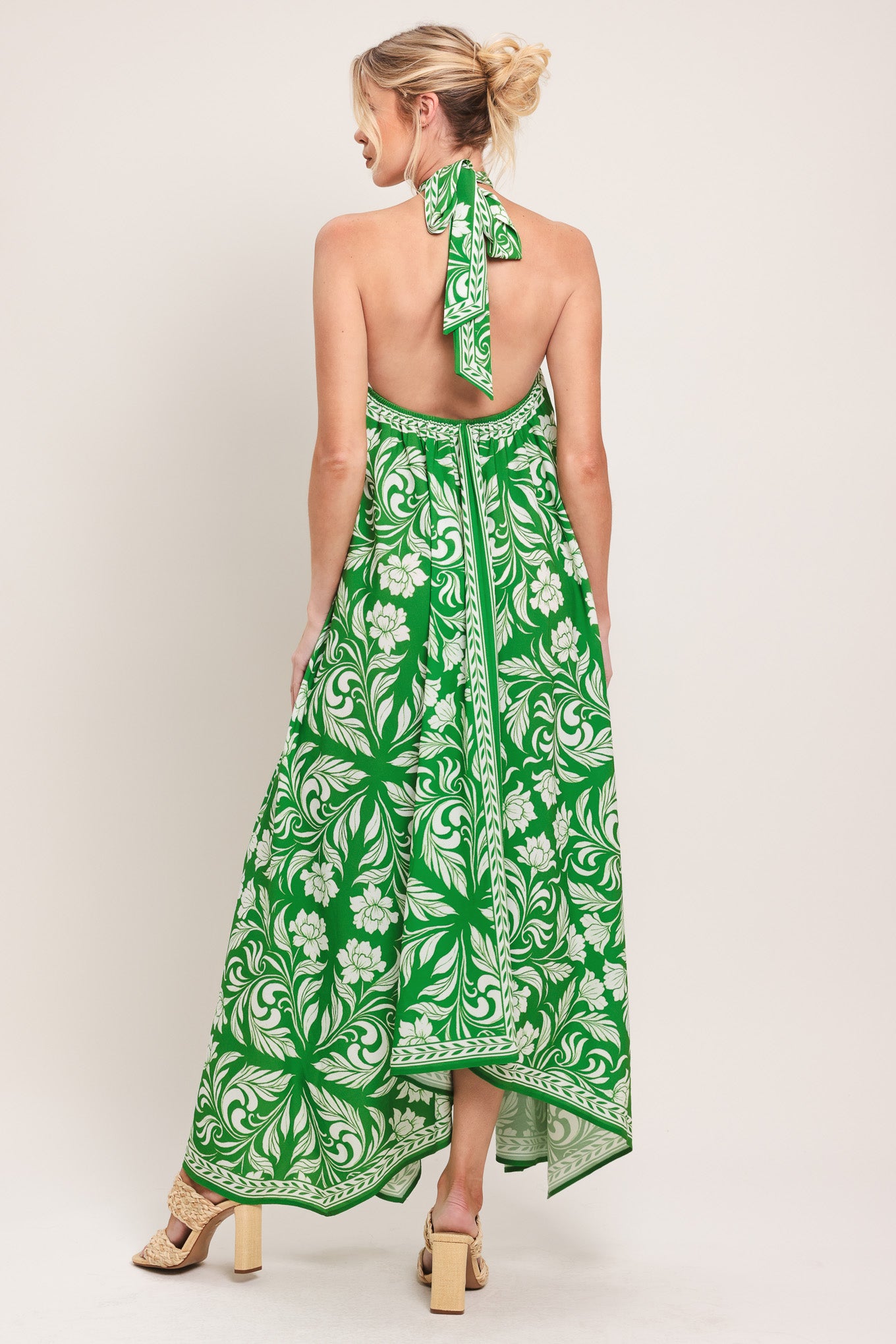 Woman wearing a green and white patterned halter neck midi dress with hardware detail, bare back, and tie closure | Flying Tomato