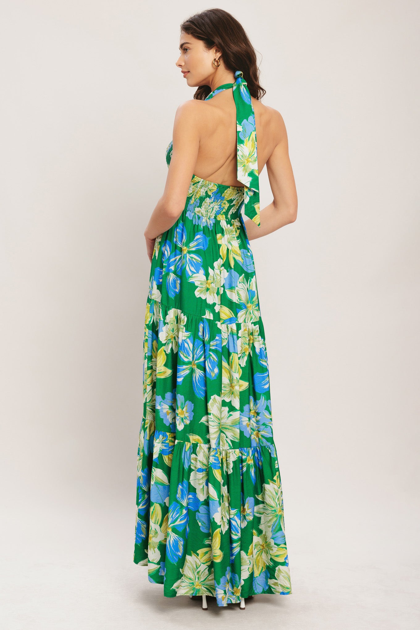 Woman wearing a green floral dress with a plain background