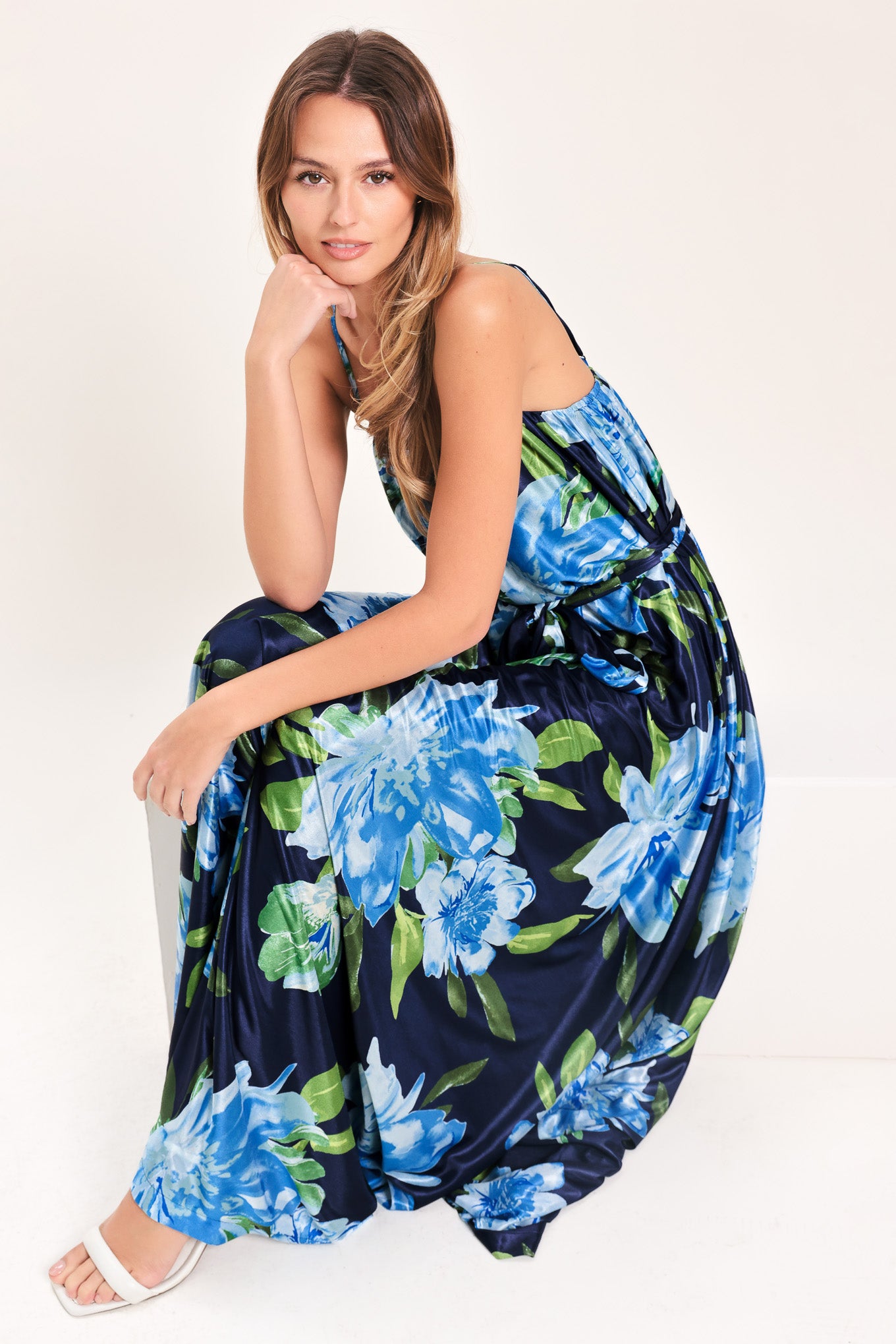 Woman wearing a navy blue with lighter blue flowers printed maxi dress with straight neckline, straps and self sash tie | Flying Tomato