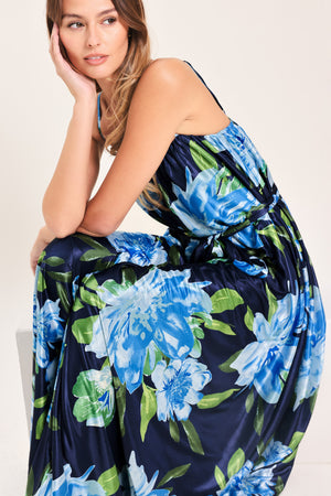 Woman wearing a navy blue with lighter blue flowers printed maxi dress with straight neckline, straps and self sash tie | Flying Tomato