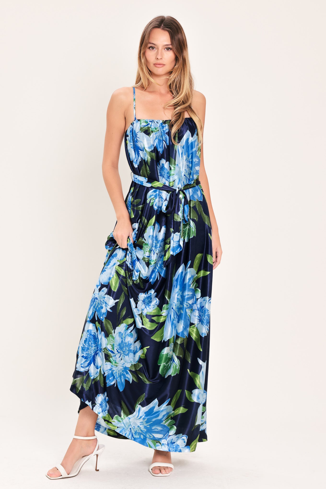 Woman wearing a navy blue with lighter blue flowers printed maxi dress with straight neckline, straps and self sash tie | Flying Tomato