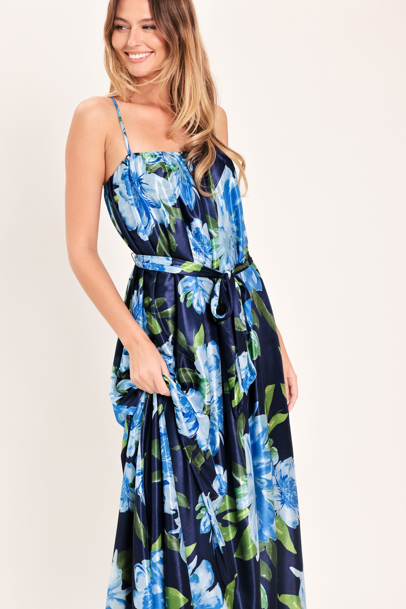 Woman wearing a navy blue with lighter blue flowers printed maxi dress with straight neckline, straps and self sash tie | Flying Tomato