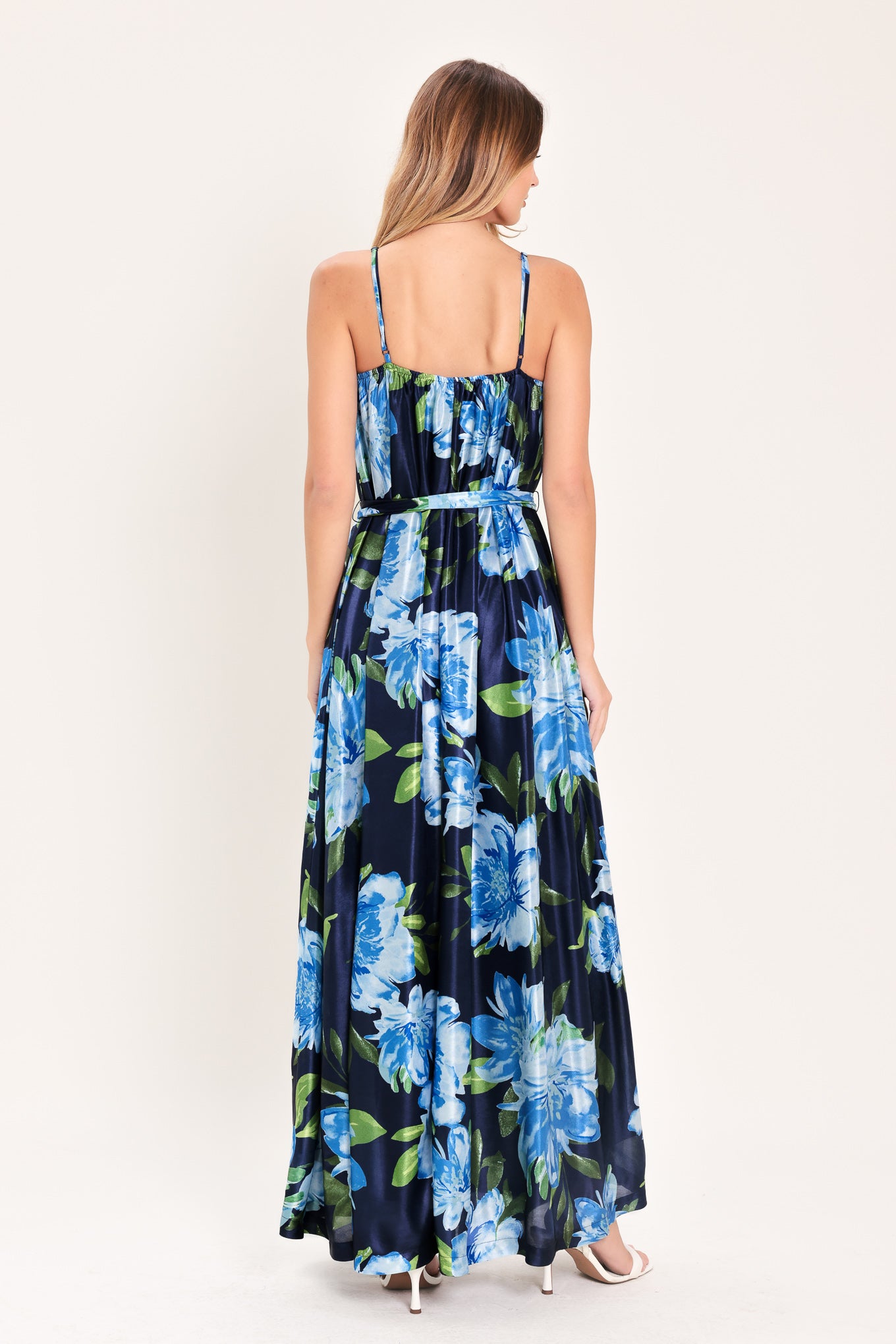 Woman wearing a navy blue with lighter blue flowers printed maxi dress with straight neckline, straps and self sash tie | Flying Tomato