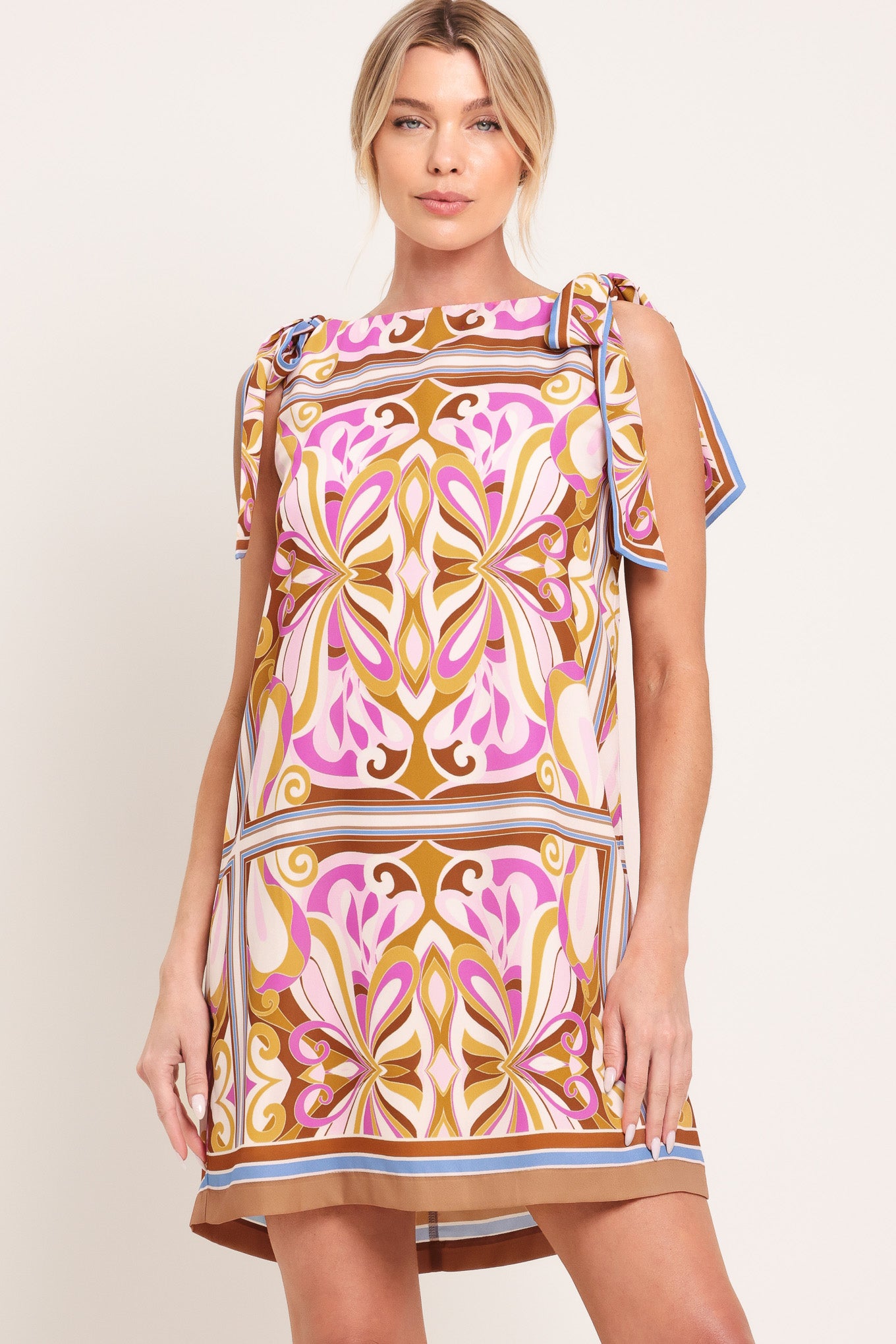 Woman wearing a sleeveless retro patterned mini dress featuring a wide neckline, shoulder ties, and back neck button closure | Flying Tomato
