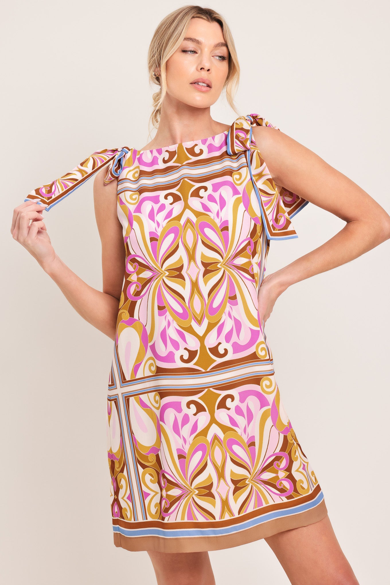 Woman wearing a sleeveless retro patterned mini dress featuring a wide neckline, shoulder ties, and back neck button closure | Flying Tomato