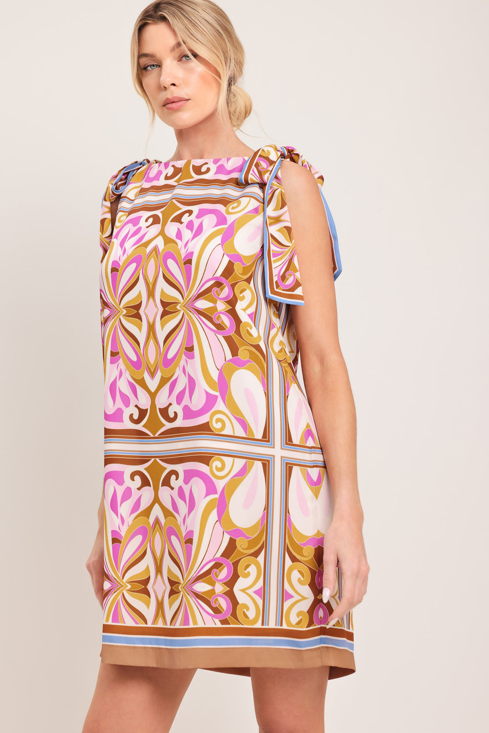 Woman wearing a sleeveless retro patterned mini dress featuring a wide neckline, shoulder ties, and back neck button closure | Flying Tomato